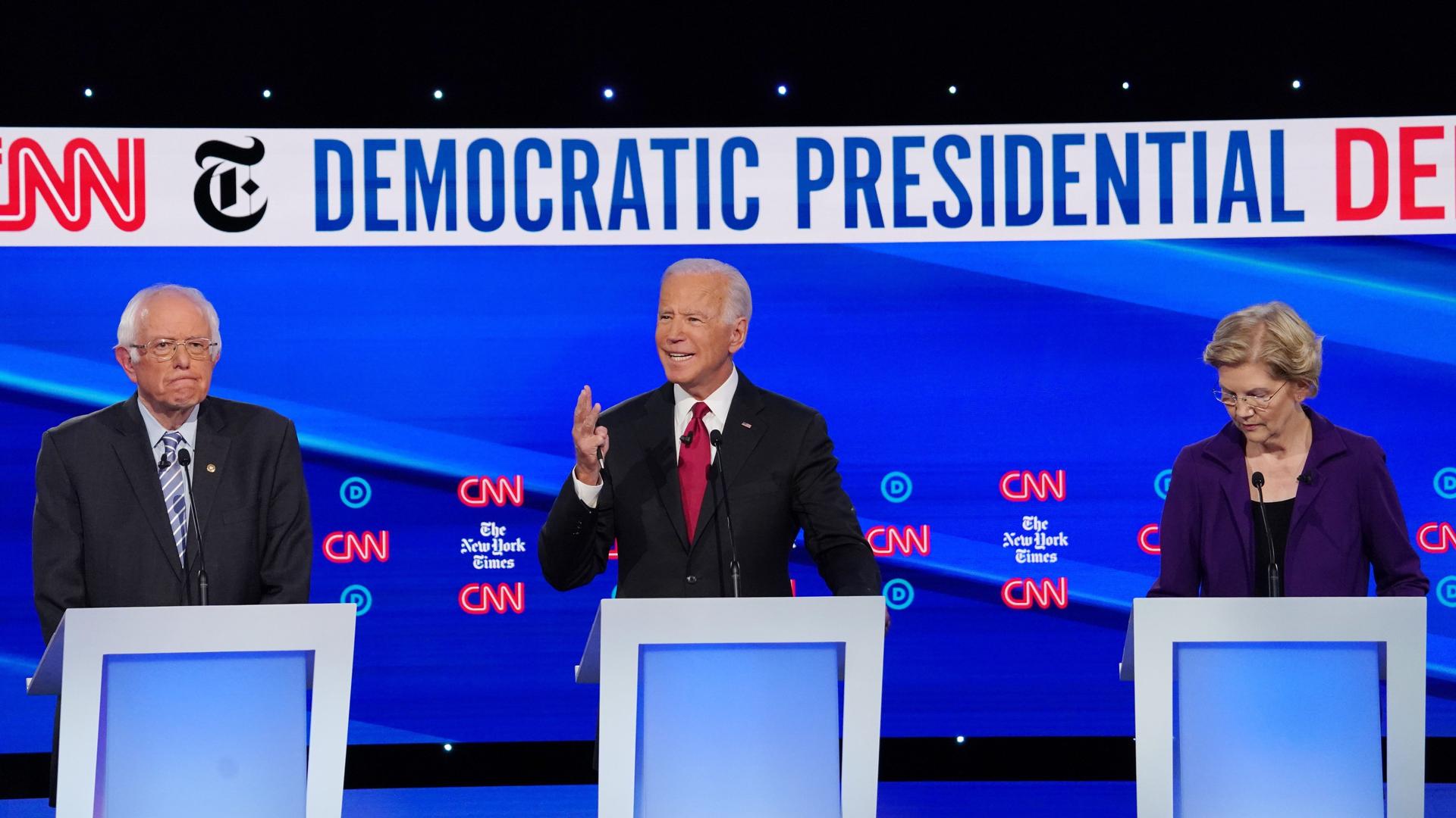 Bernie Sanders, Joe Biden and Elizabeth Warren stand behind podiums
