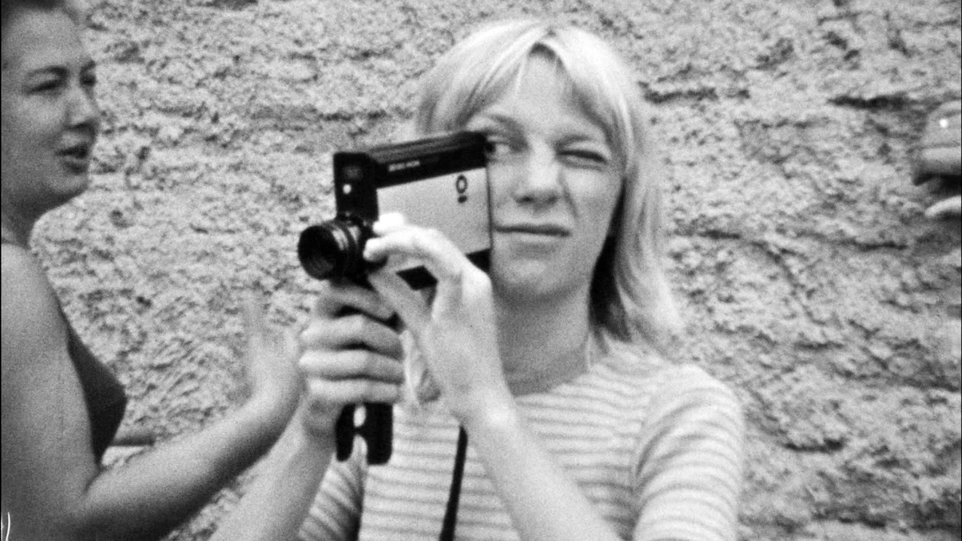 A woman holds a video camera in her hand in a black and white photo 