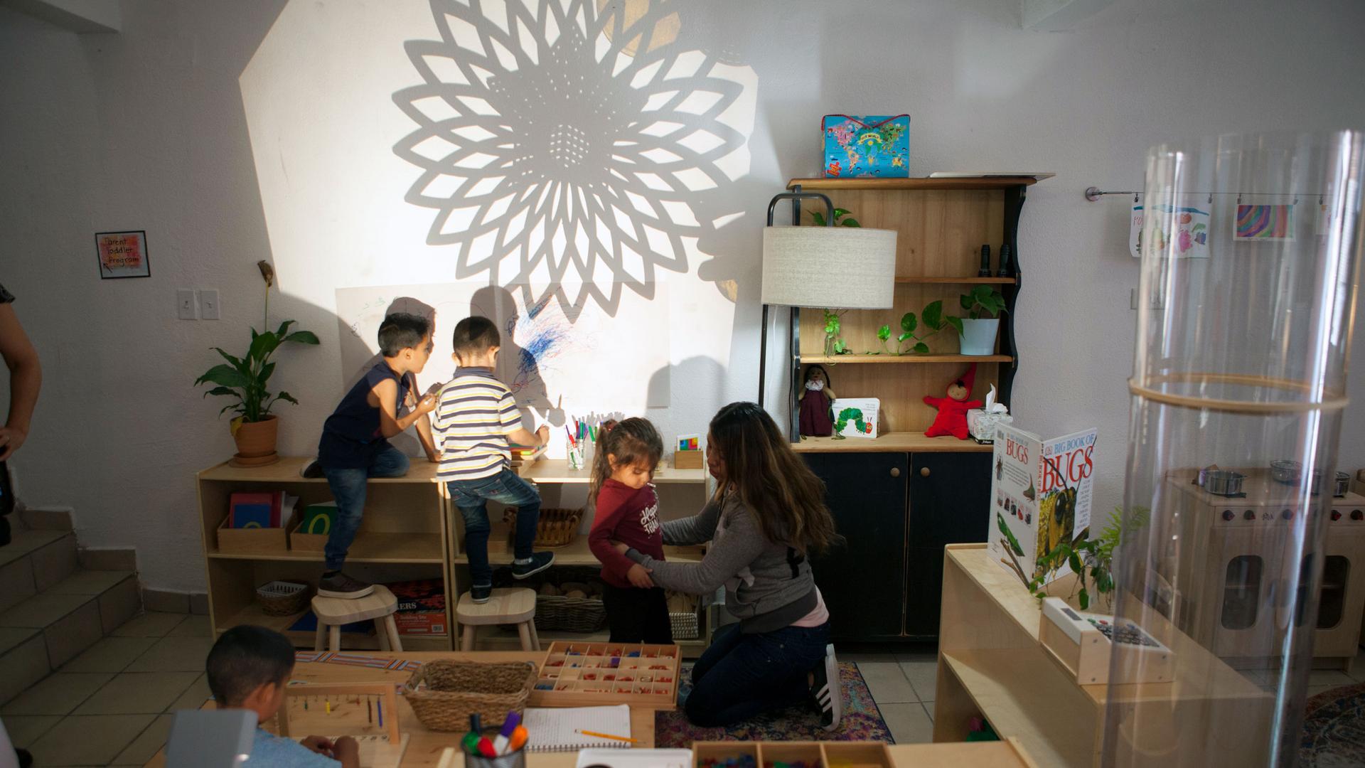 Several children are shown playing with a flower-shaped light projection on a wall.