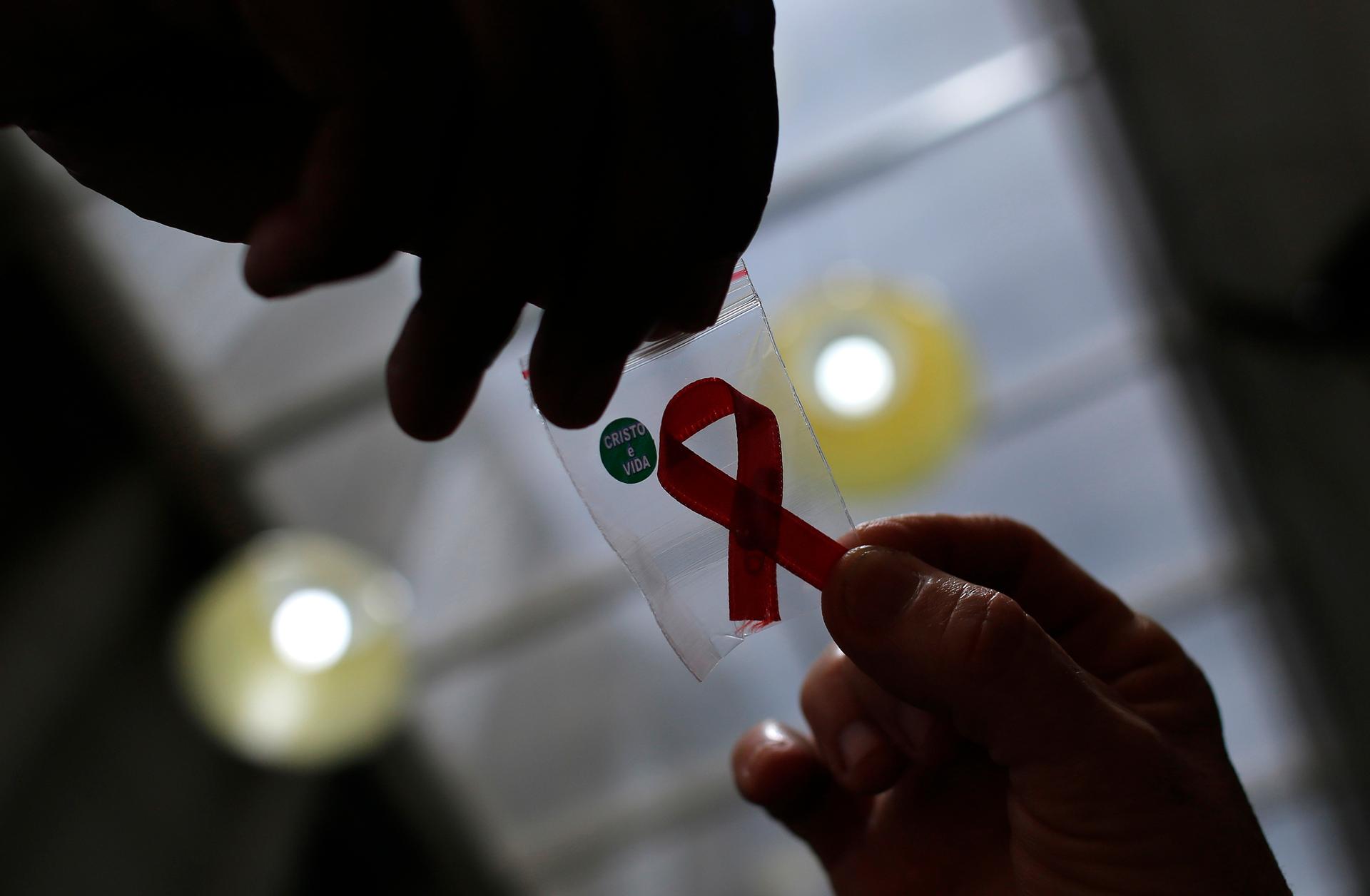 A nurse hands out a red ribbon to a woman, to mark World AIDS Day, at the entrance of Emilio Ribas Hospital, in Sao Paulo December 1, 2014.