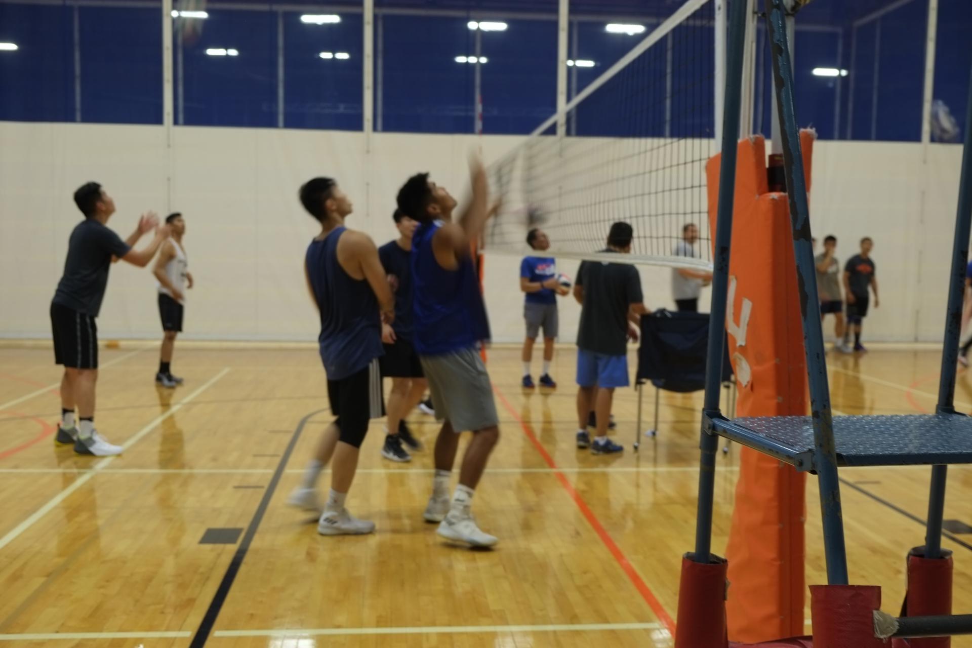 Asian men play a volleyball game in uniforms on a court