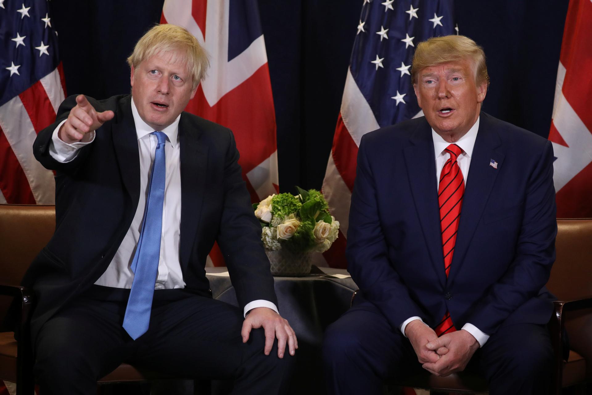 Donald Trump and Boris Johnson sit next to each other.