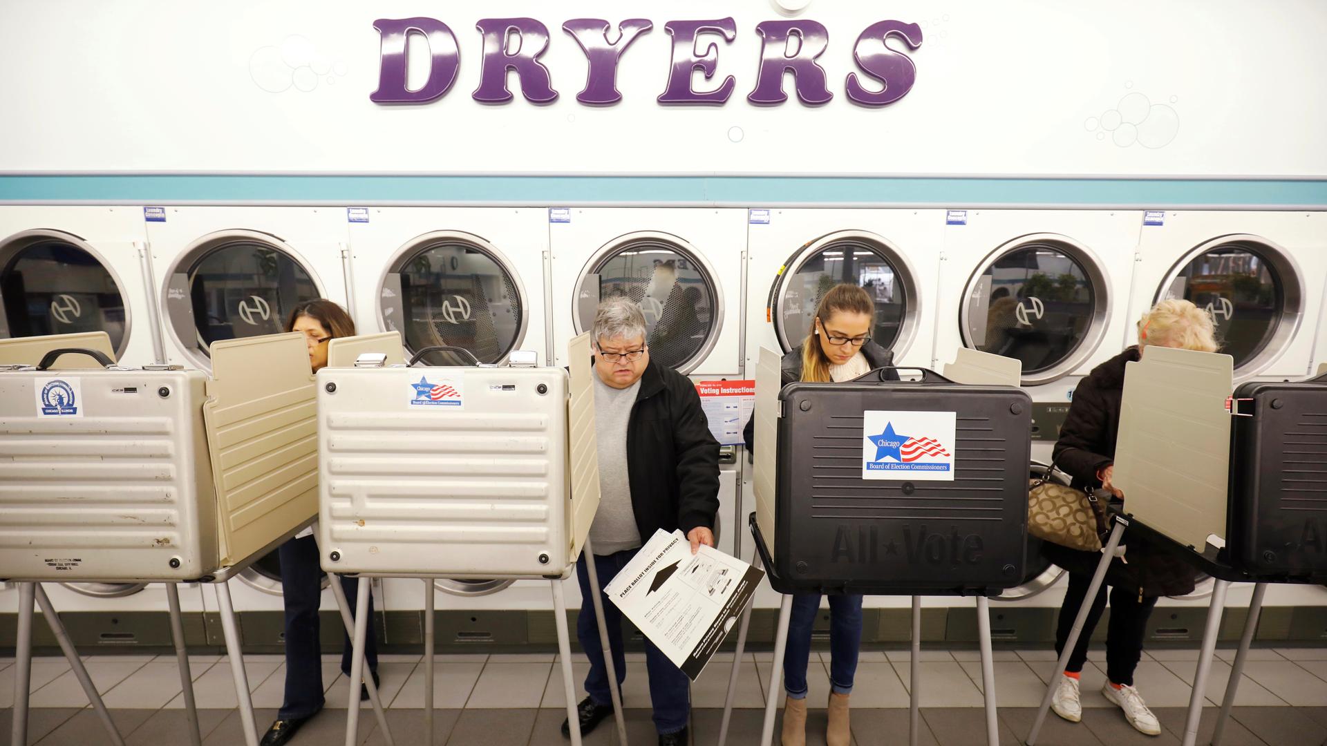 People stand in voting booth casting ballots 