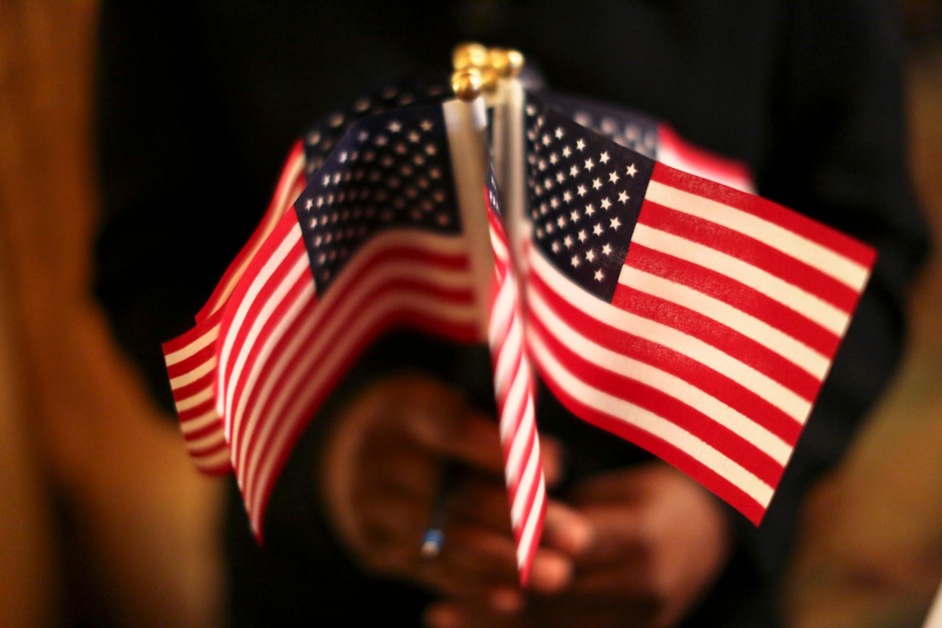 A woman holds a cluster of US flags during a US Citizenship and Immigration Services naturalization ceremony in Oakland, California, on Aug. 13, 2013.