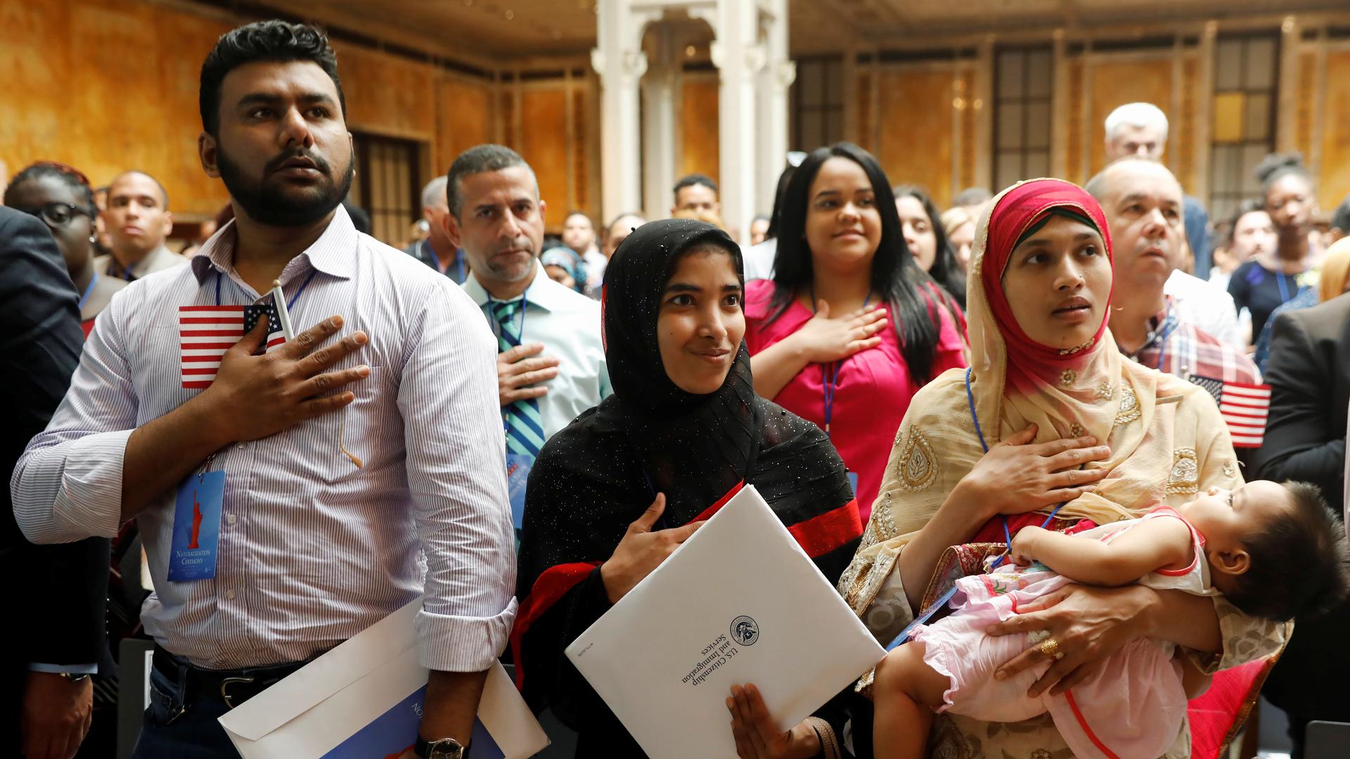 New citizens stand during the National Anthem at a US Citizenship and Immigration Services (USCIS) naturalization ceremony at the New York Public Library in Manhattan, New York, on July 3, 2018.