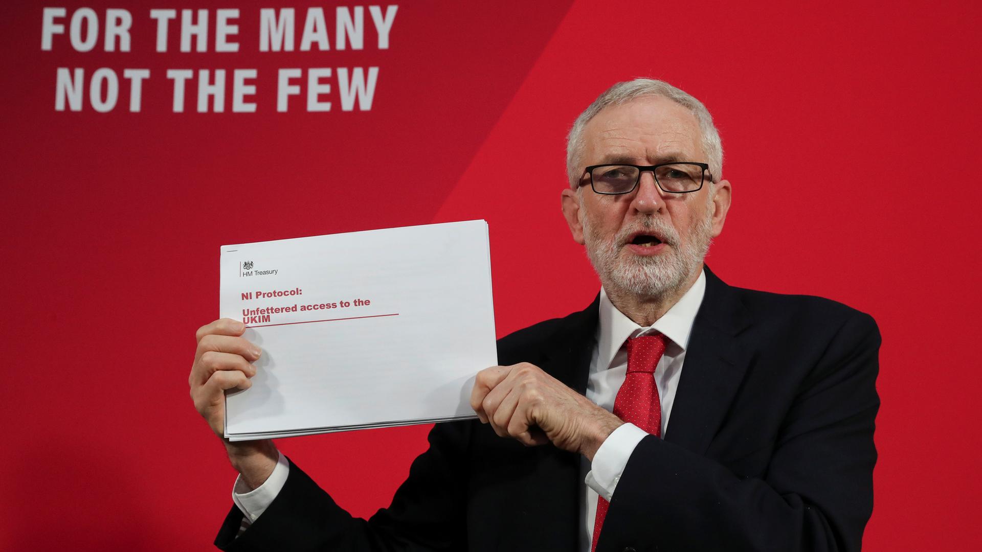 Britain's opposition Labour Party leader Jeremy Corbyn is shown holding a white piece of paper off to his side with red lettering.