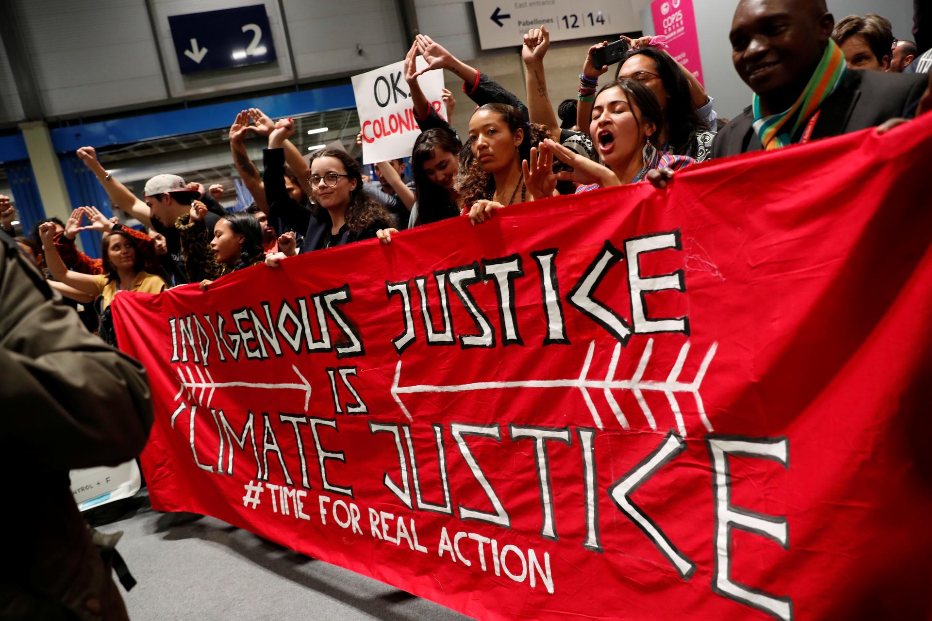 Protesters in Madrid climate talks hold large red banner as they walk