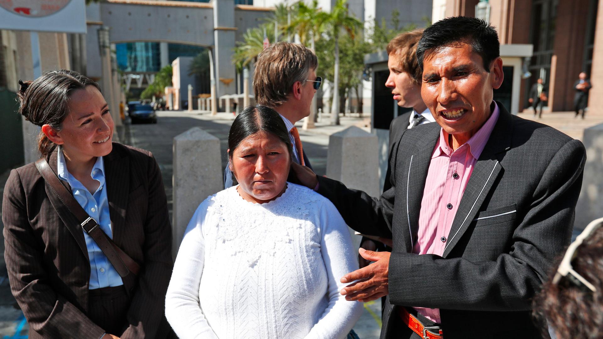 Eloy Rojas Mamani, right, gestures toward his wife Etelvina Ramos Mamani are shown standing next to each other with Eloy wearing a dark suit and Etelvina wearing a white top.