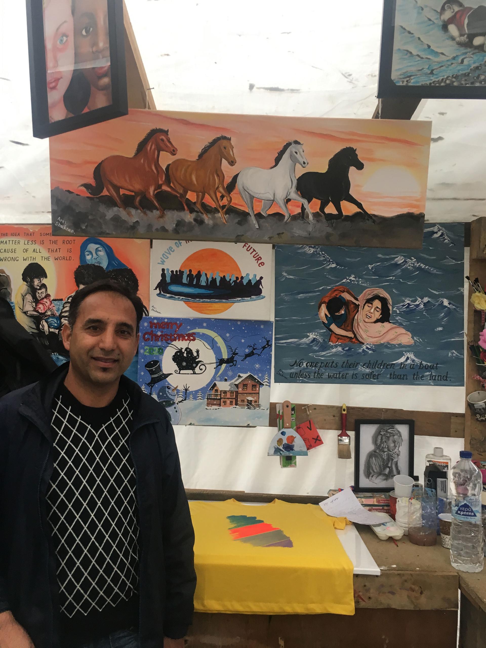A man is shown standing in front of several pieces of art work including an illustration of four horses running.