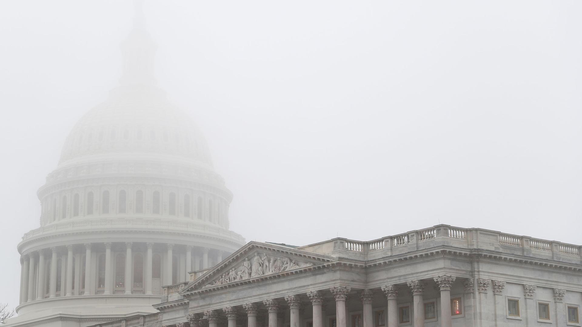 Heavy fog sits over the top of the US Capitol dome making it barely visible. 