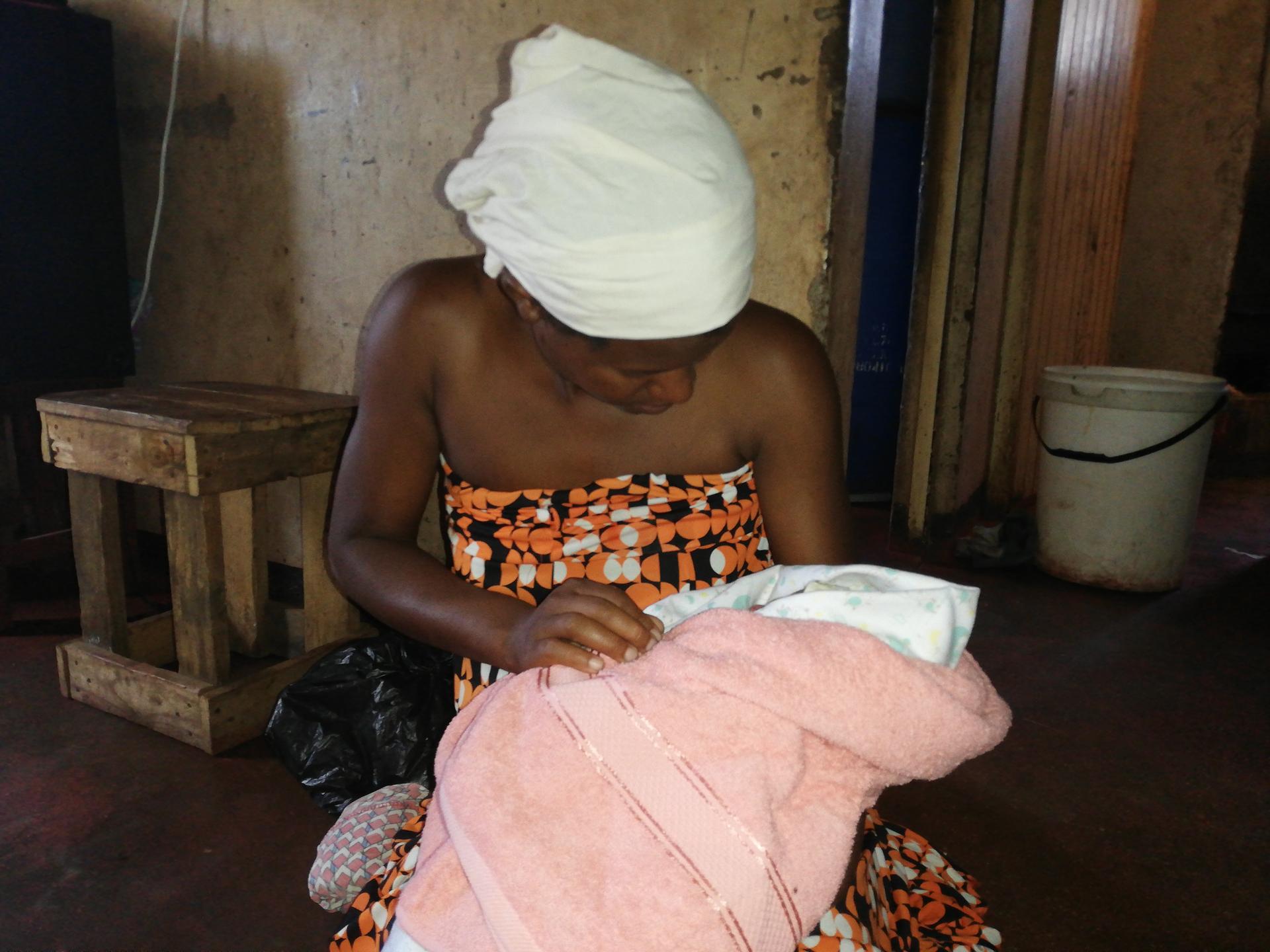 A young woman wrapped in a towel holds her newborn baby