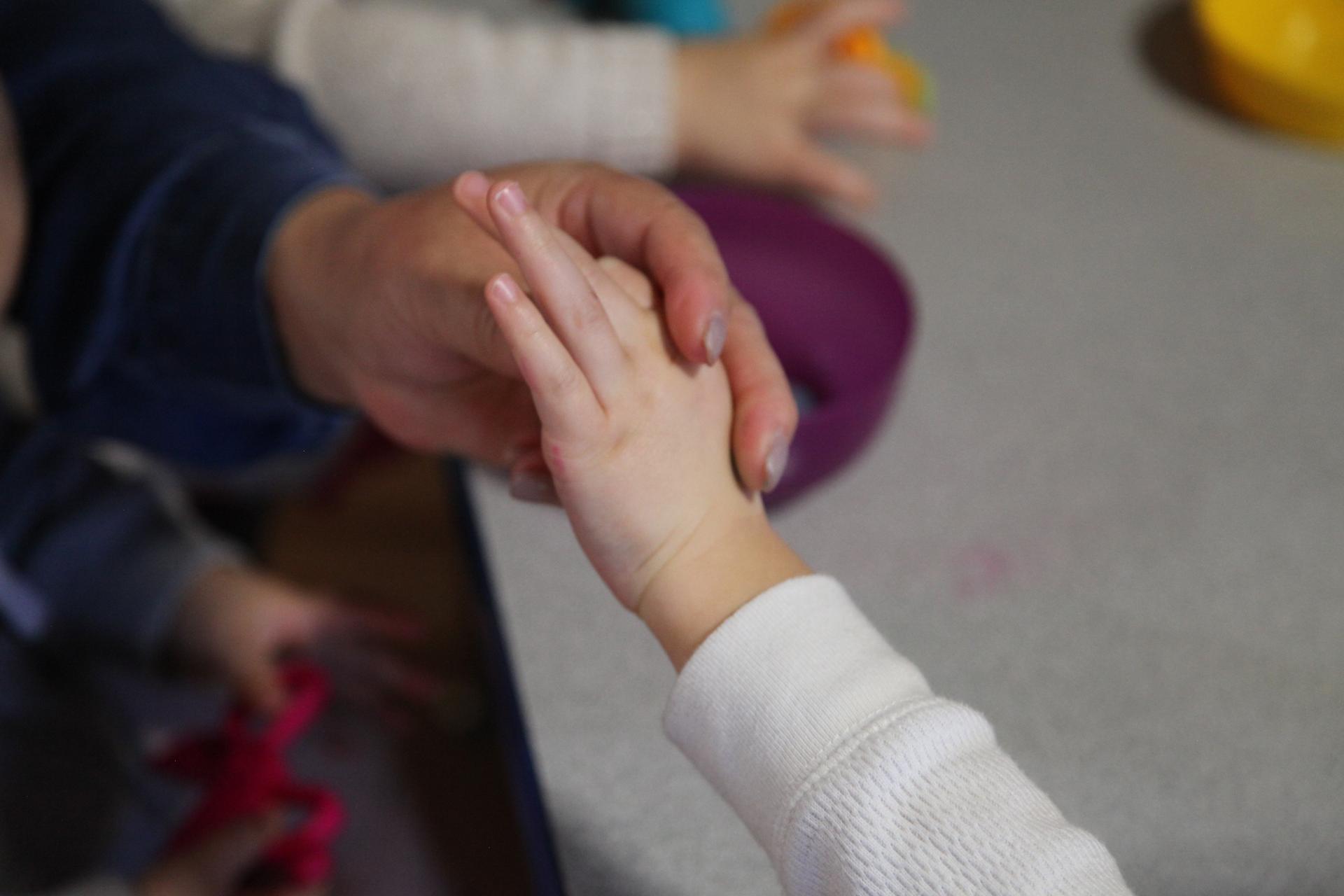 A woman touches a child's hand