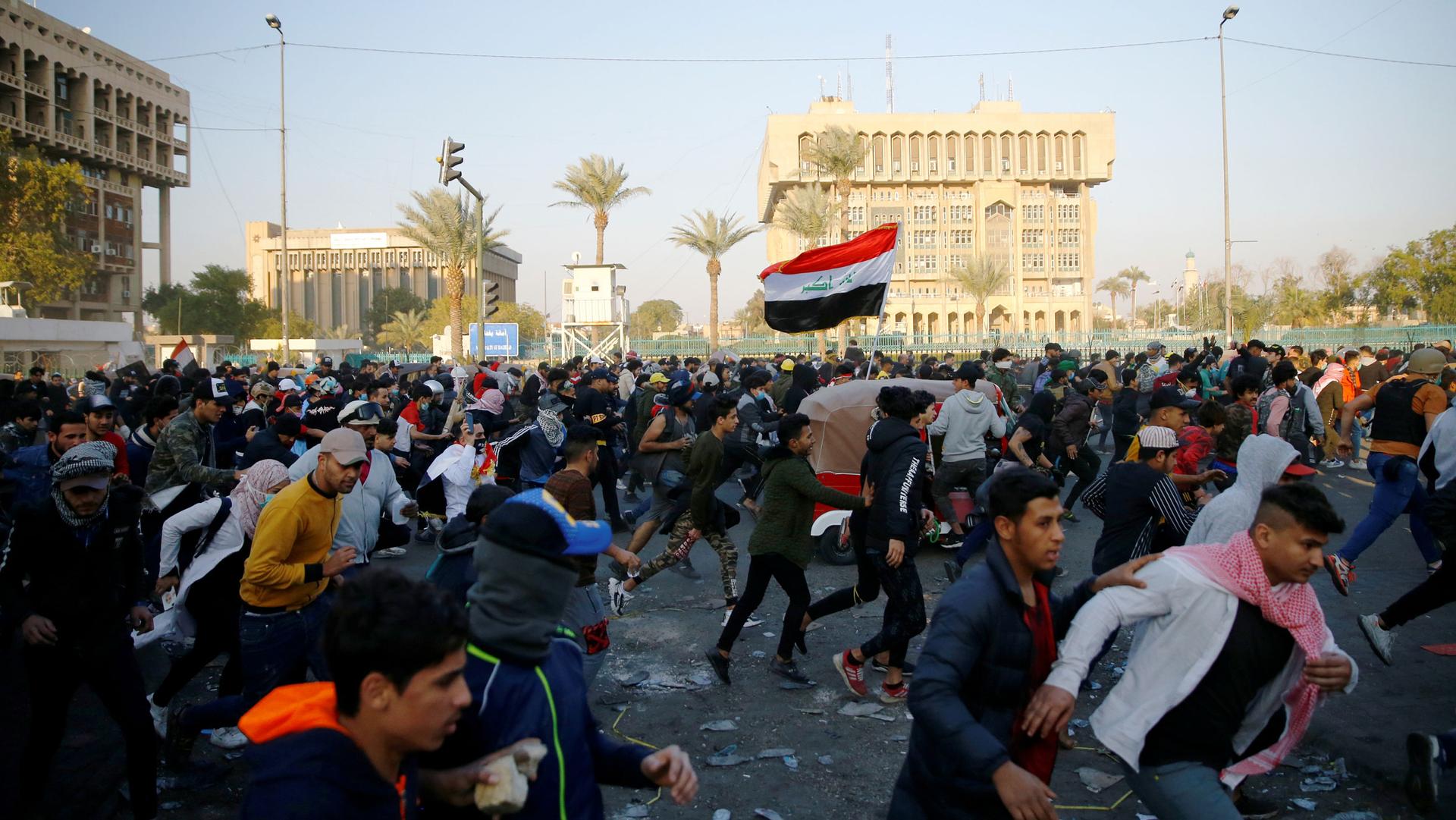 Iraqi demonstrators run for cover as they clash with Iraqi security forces