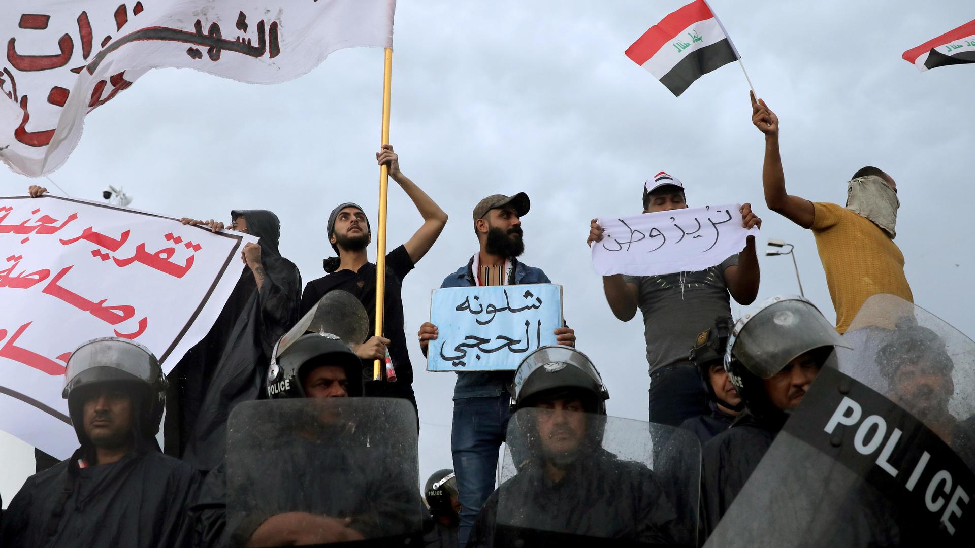 Iraqi policemen stand in front of demonstrators during a protest over corruption, lack of jobs, and poor services, in Kerbala, Iraq, on October 25, 2019.