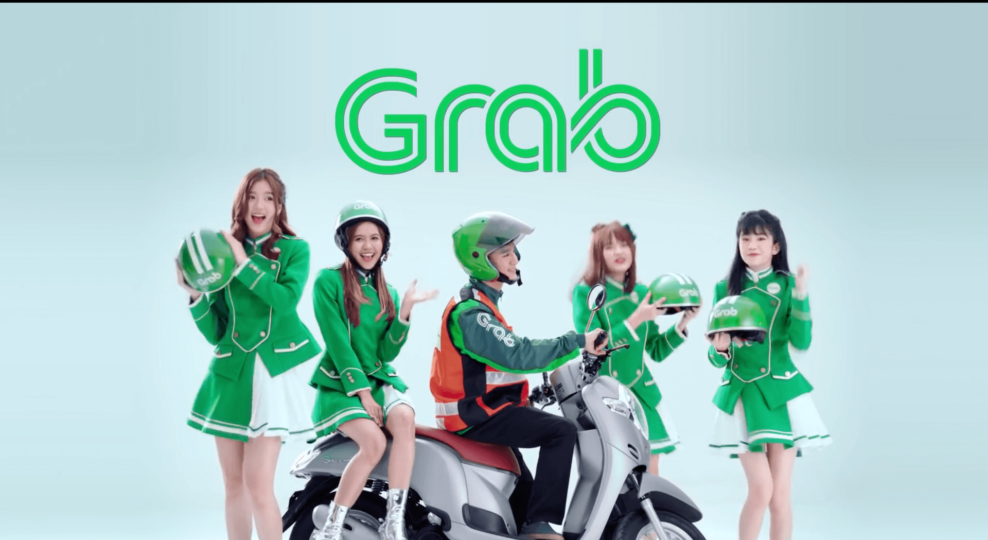 A popular girl band poses near a Grab driver wearing green uniform