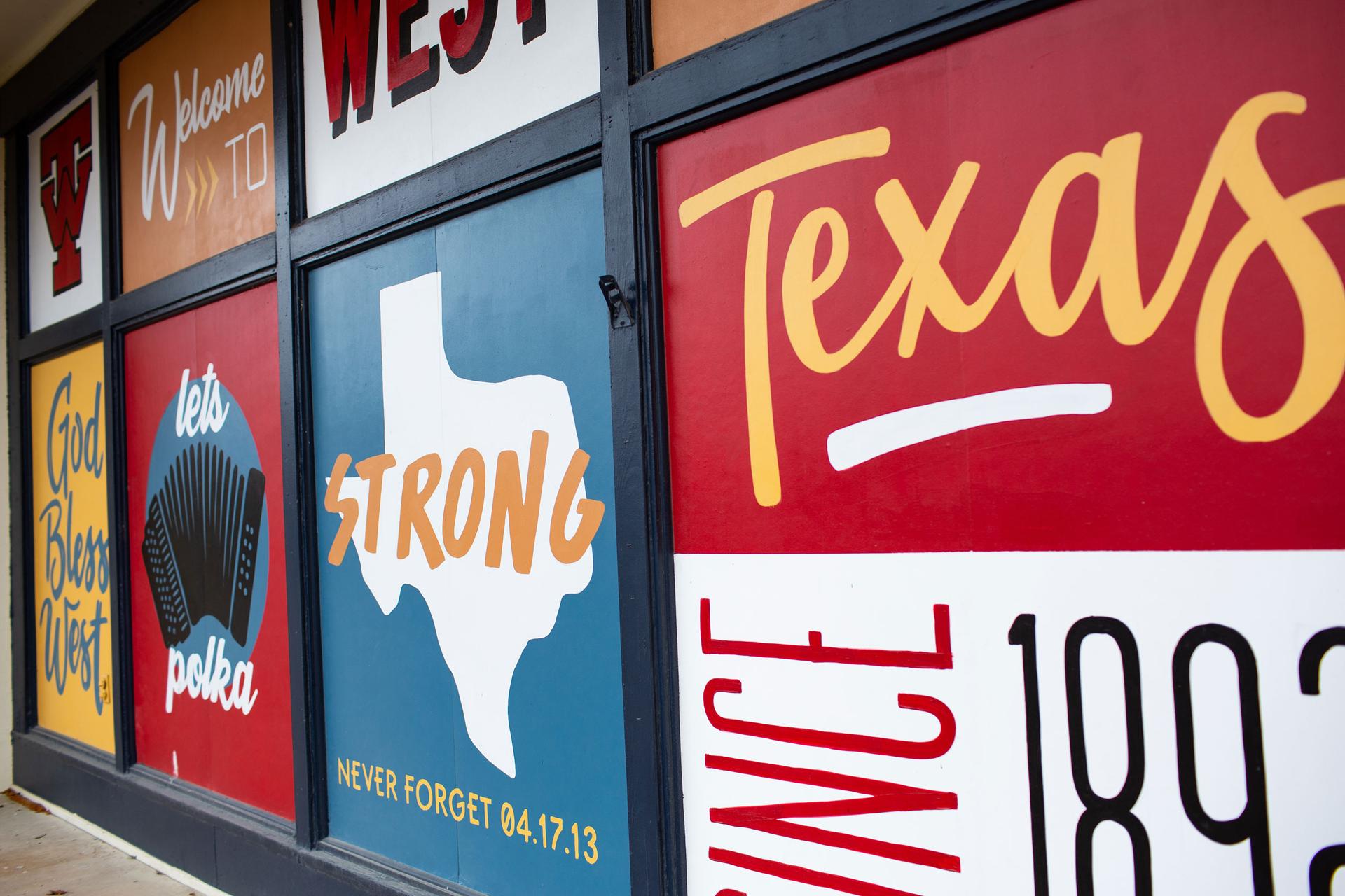 A wall is show with several messages on it, including one that reads, 'Welcome to West, Texas.