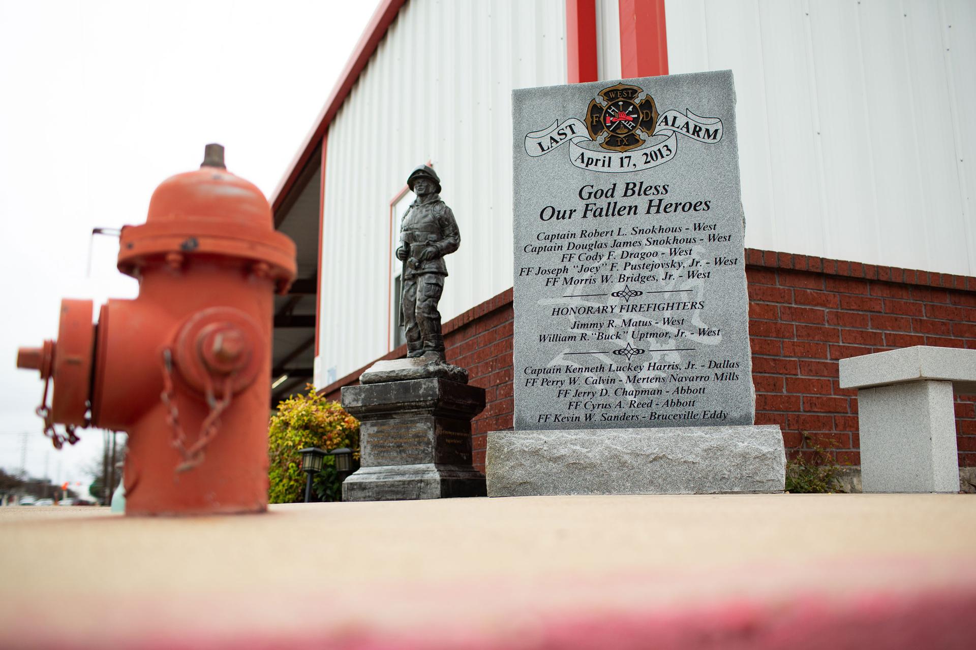 A statue of a fireman is next to a red fire hydrant.
