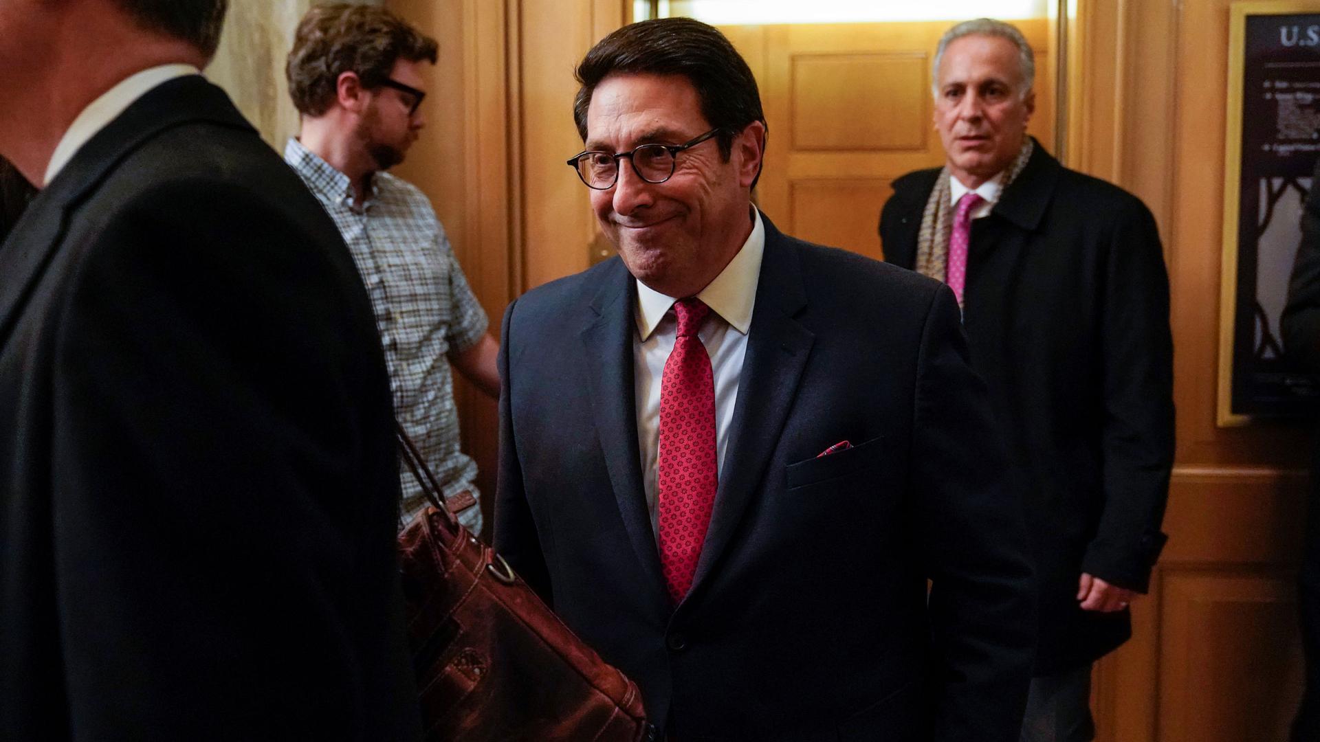 US President Donald Trump's personal attorney Jay Sekulow is shown wearing a dark suit and walking among several people.