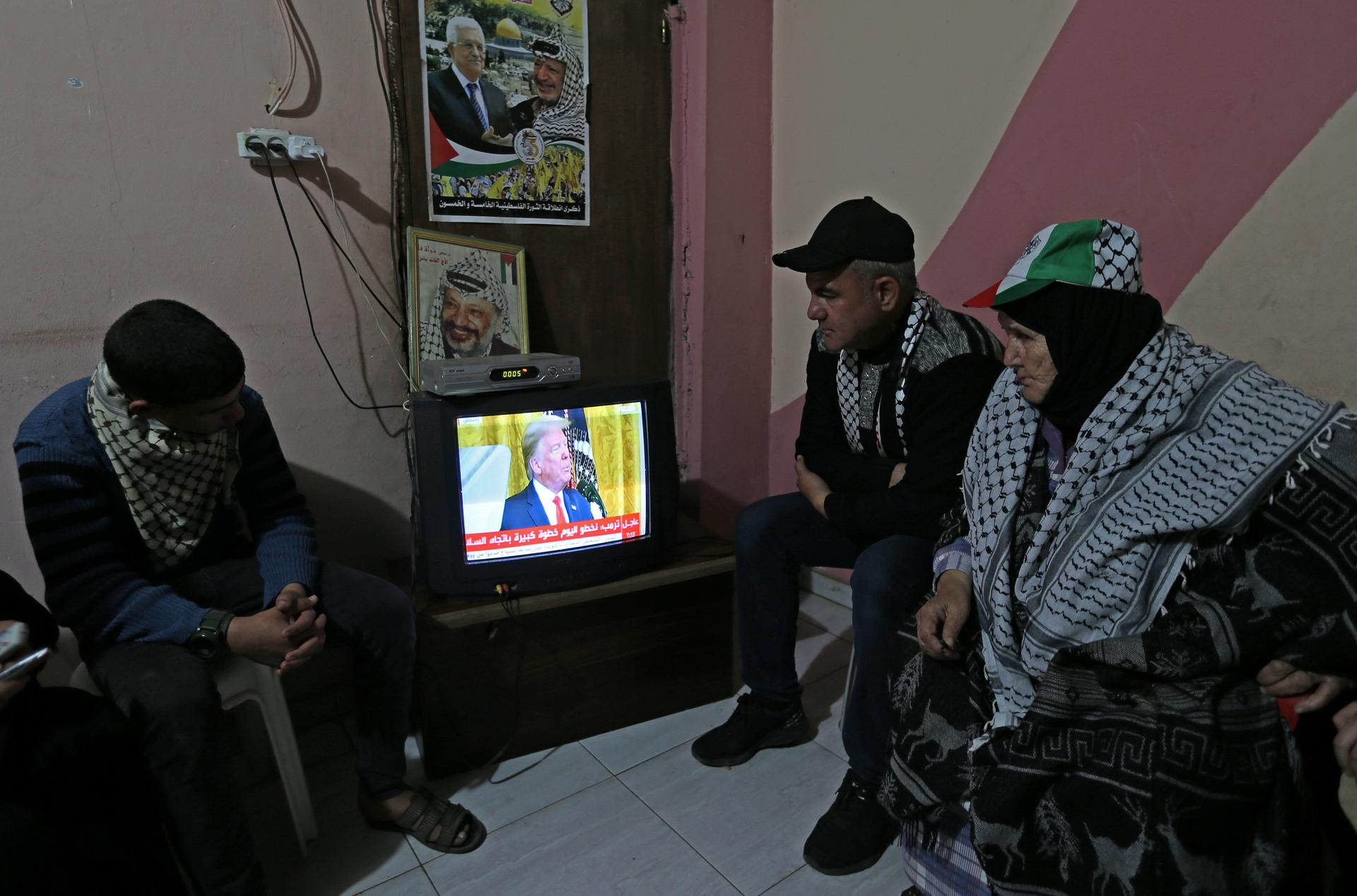 Palestinians watch a television broadcasting the announcement of Middle East peace plan by US President Donald Trump, in the southern Gaza Strip on Jan. 28, 2020.