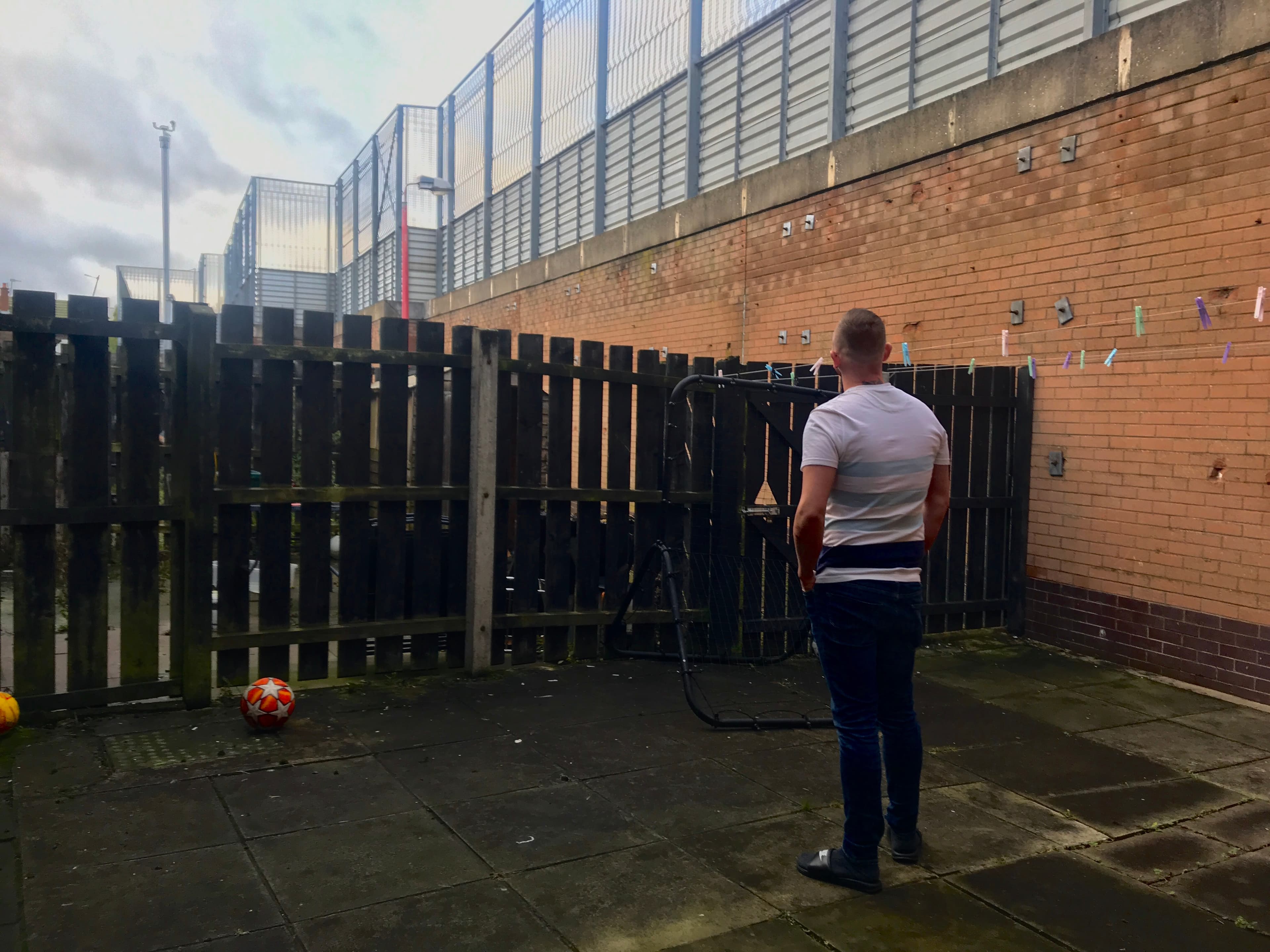 A man stands with back to camera facing peace wall