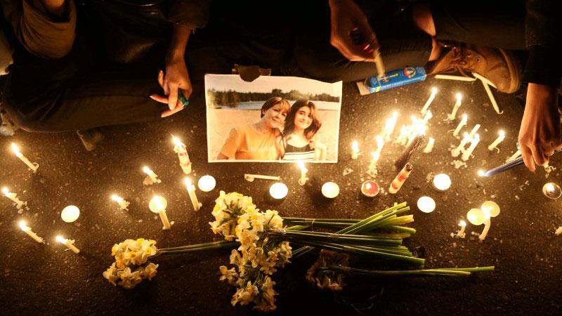 Candles surround a photo of a woman and girl.