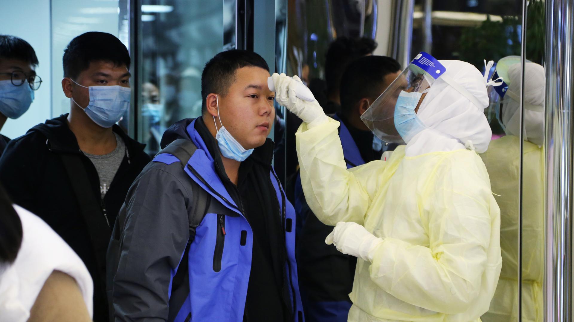 A man wears a mask as he gets checked at airport for virus