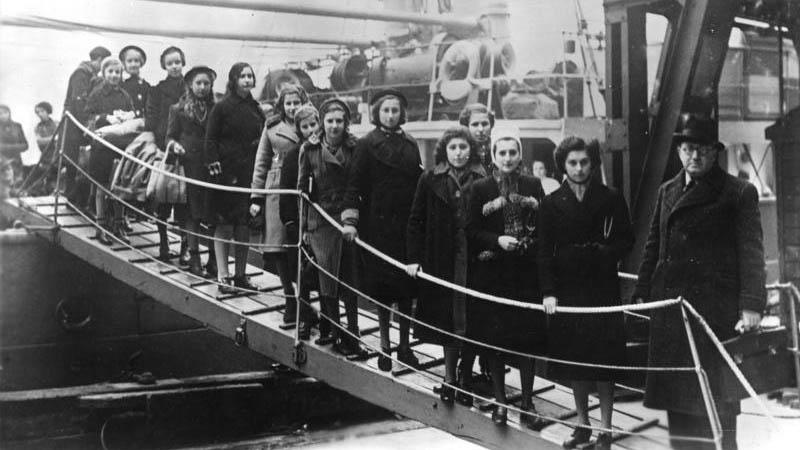 A black and white image of girls walking down a ships gangway