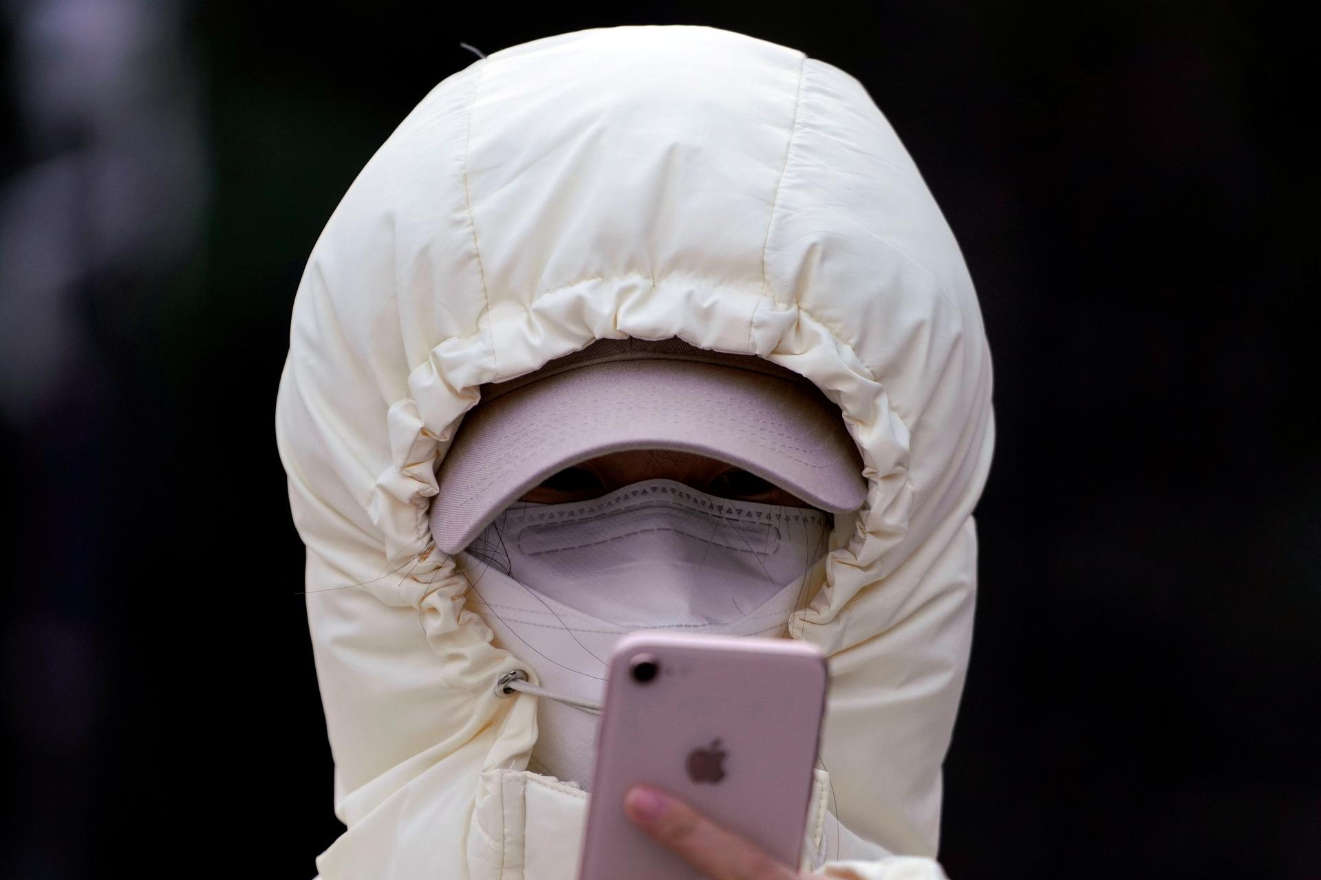 A woman wearing a mask checks her mobile phone in Shanghai, Jan. 29, 2020.
