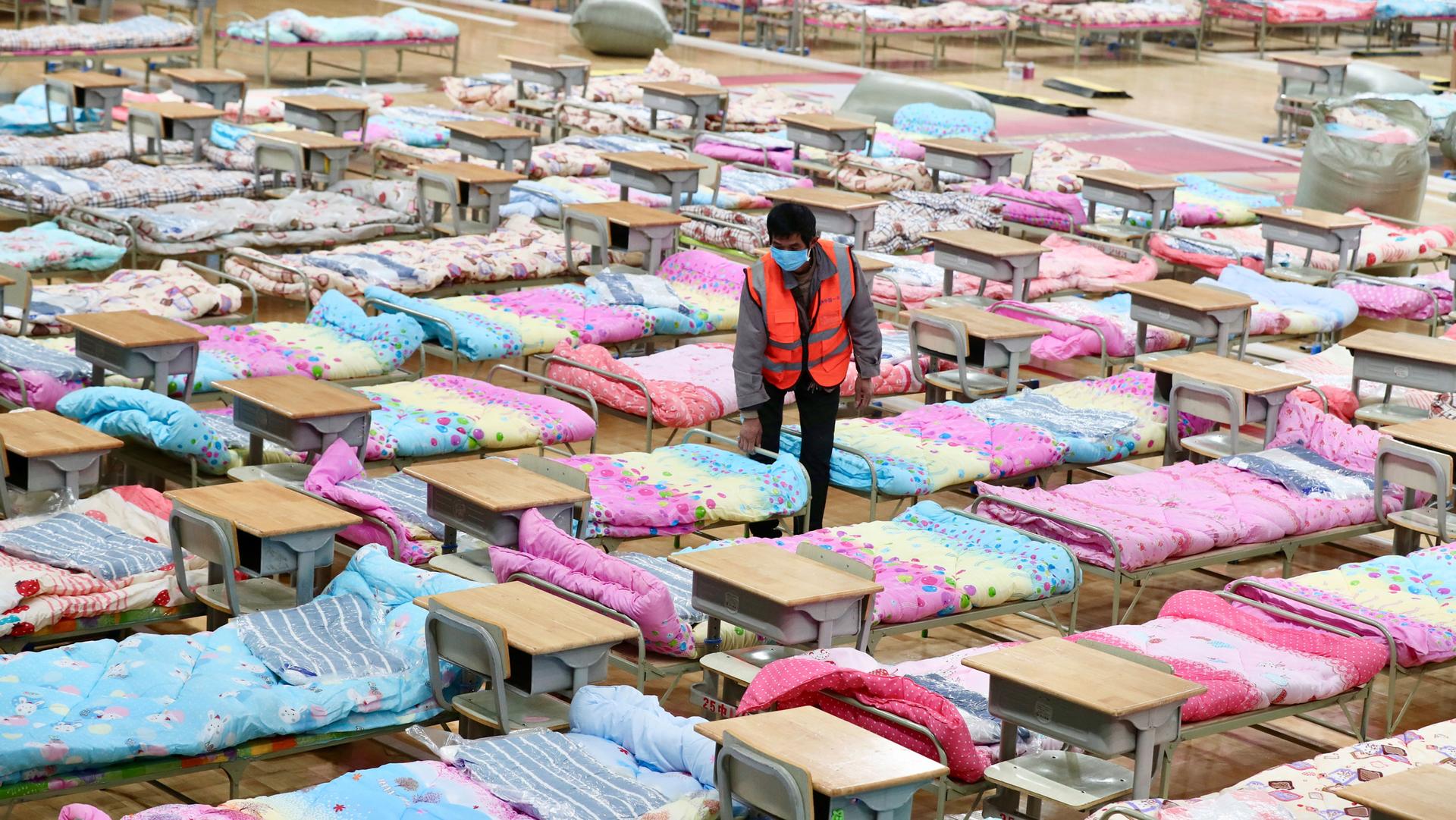 A worker amid a room of cots