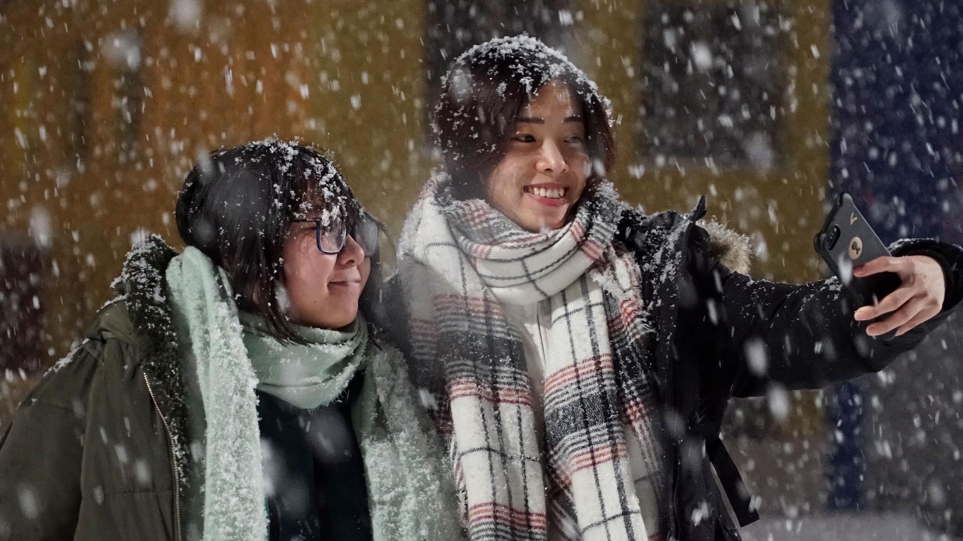 Tourists from China take a selfie as large snow flakes are falling all around them.