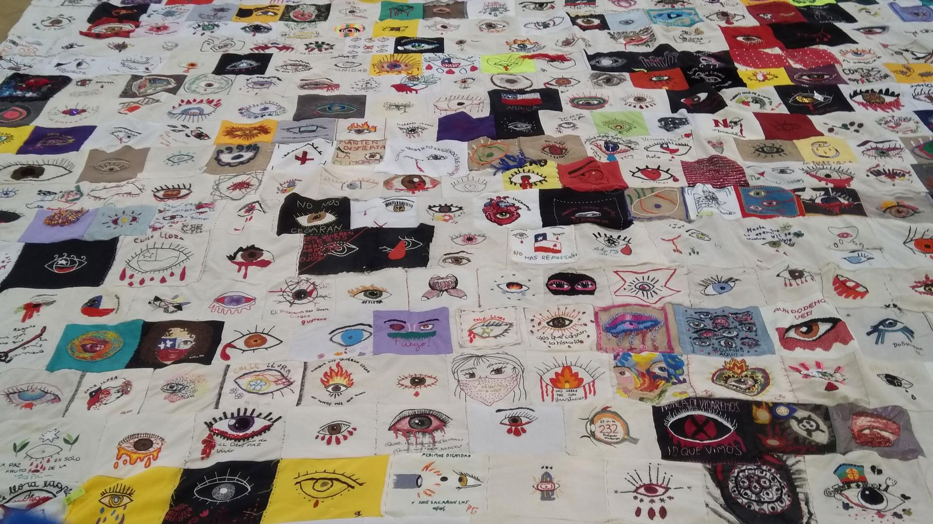 A close-up section of several rows of embroided protest art showing bleeding eyes.