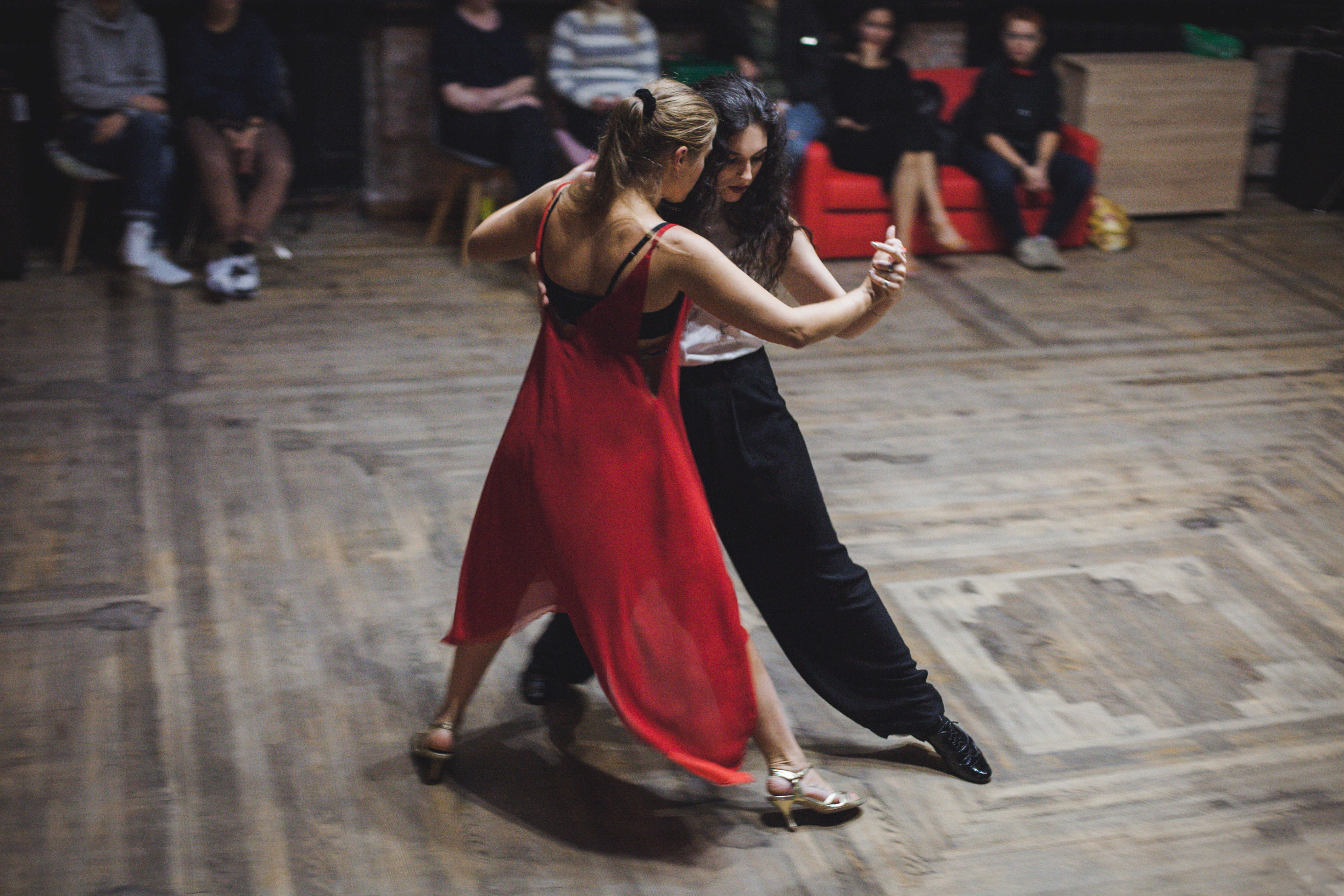 A woman in red dances with a woman in black at a dance studio