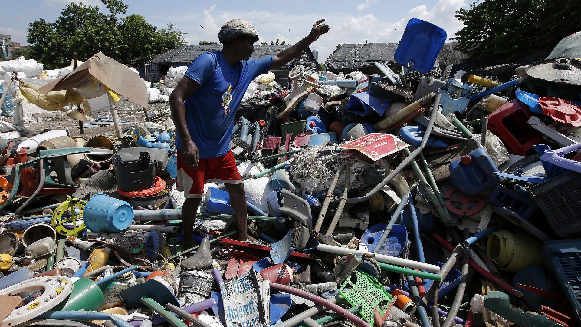 A man picks through a huge heap of plastic trash