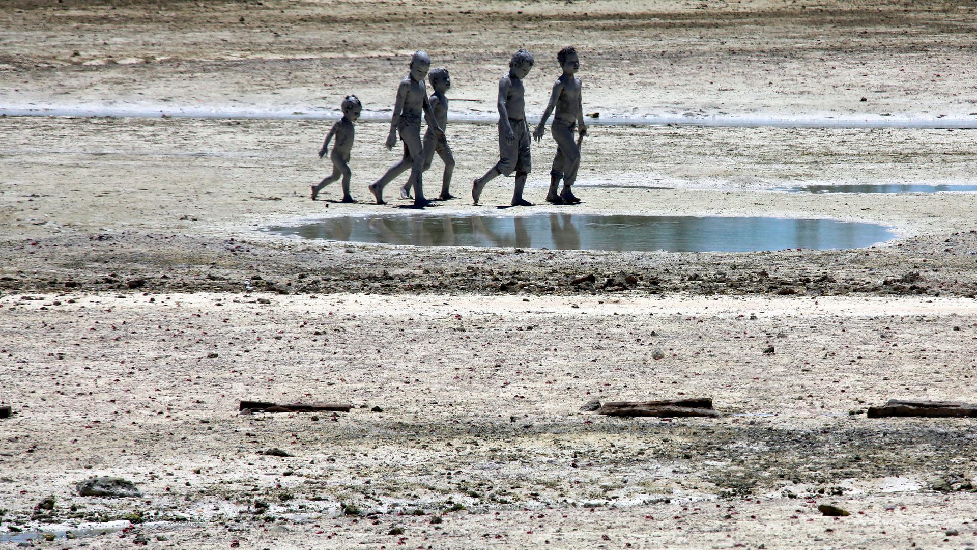 Four young people walk on an island with puddles