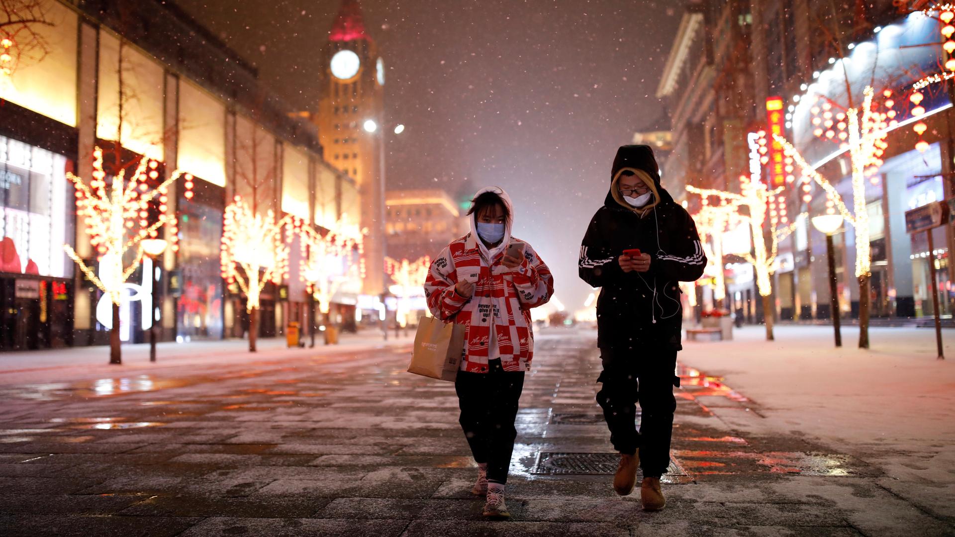 People wearing face masks walk along a street, as China is hit by an outbreak of the new coronavirus, in Beijing, Feb. 5, 2020. 