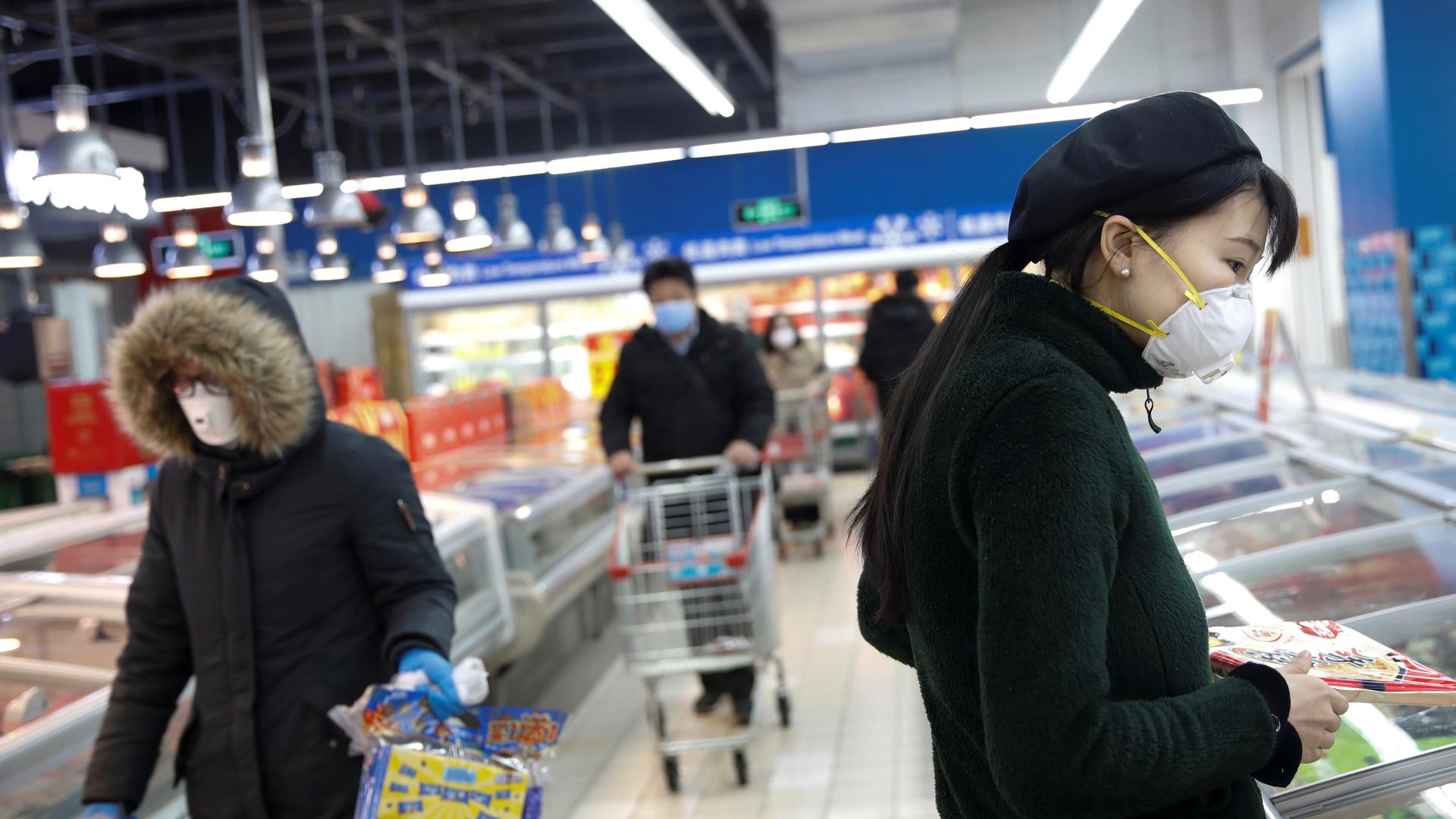 People wearing face masks look for products at a supermarket, as the country is hit by an outbreak of the new coronavirus, in Beijing, Feb. 19, 2020. 