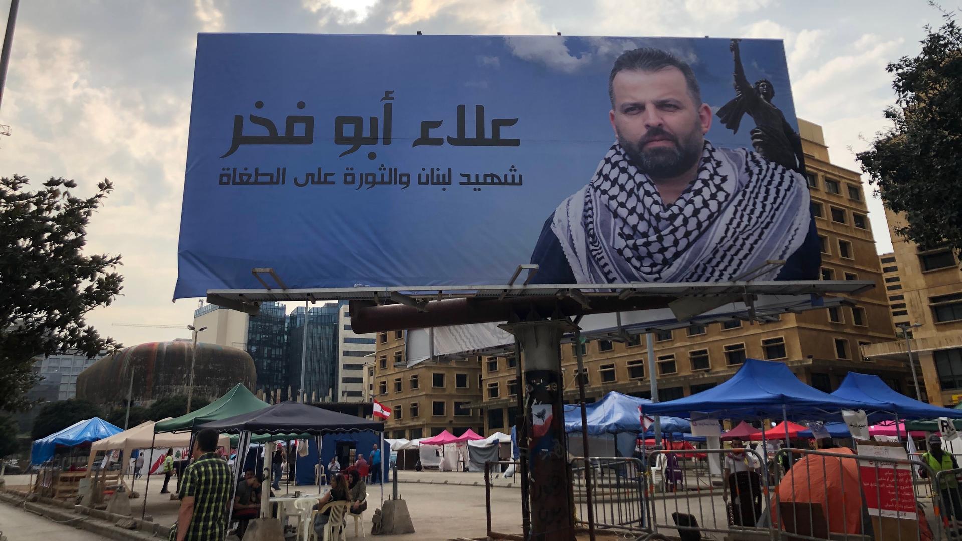 Vendors and civil society tents set up in Martyrs' Square under the photo of man who was killed during a roadblock in a suburb of Beirut.