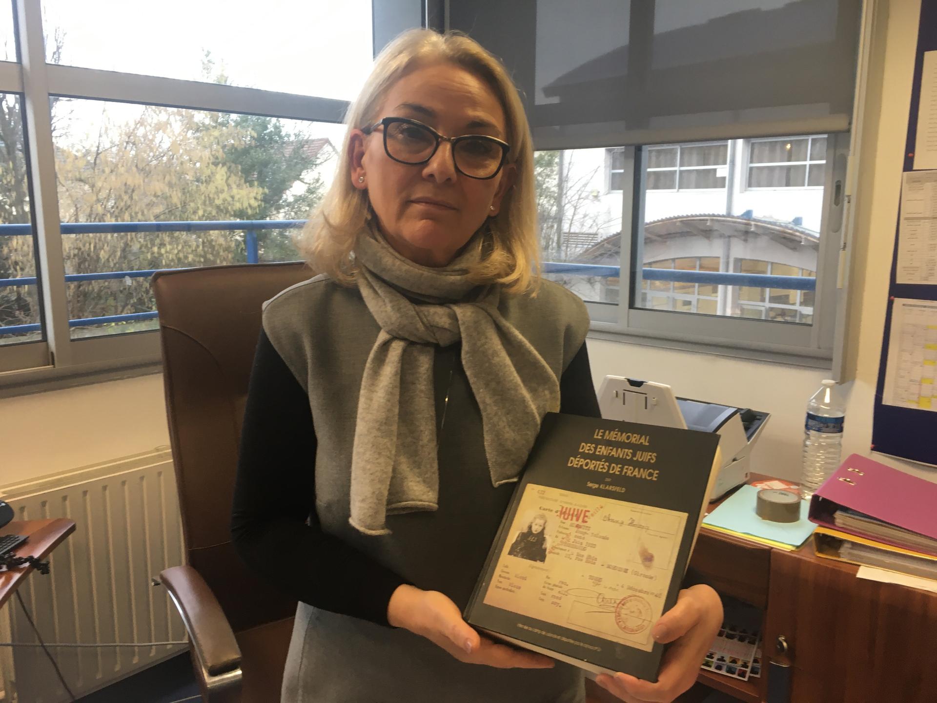 Sarah-Laure Attias, the director of a private Jewish school on the outskirts of Paris, holds a book listing the names of every Jewish child deported from France during World War II. Attias says students at her school need to be extra prepared when it come