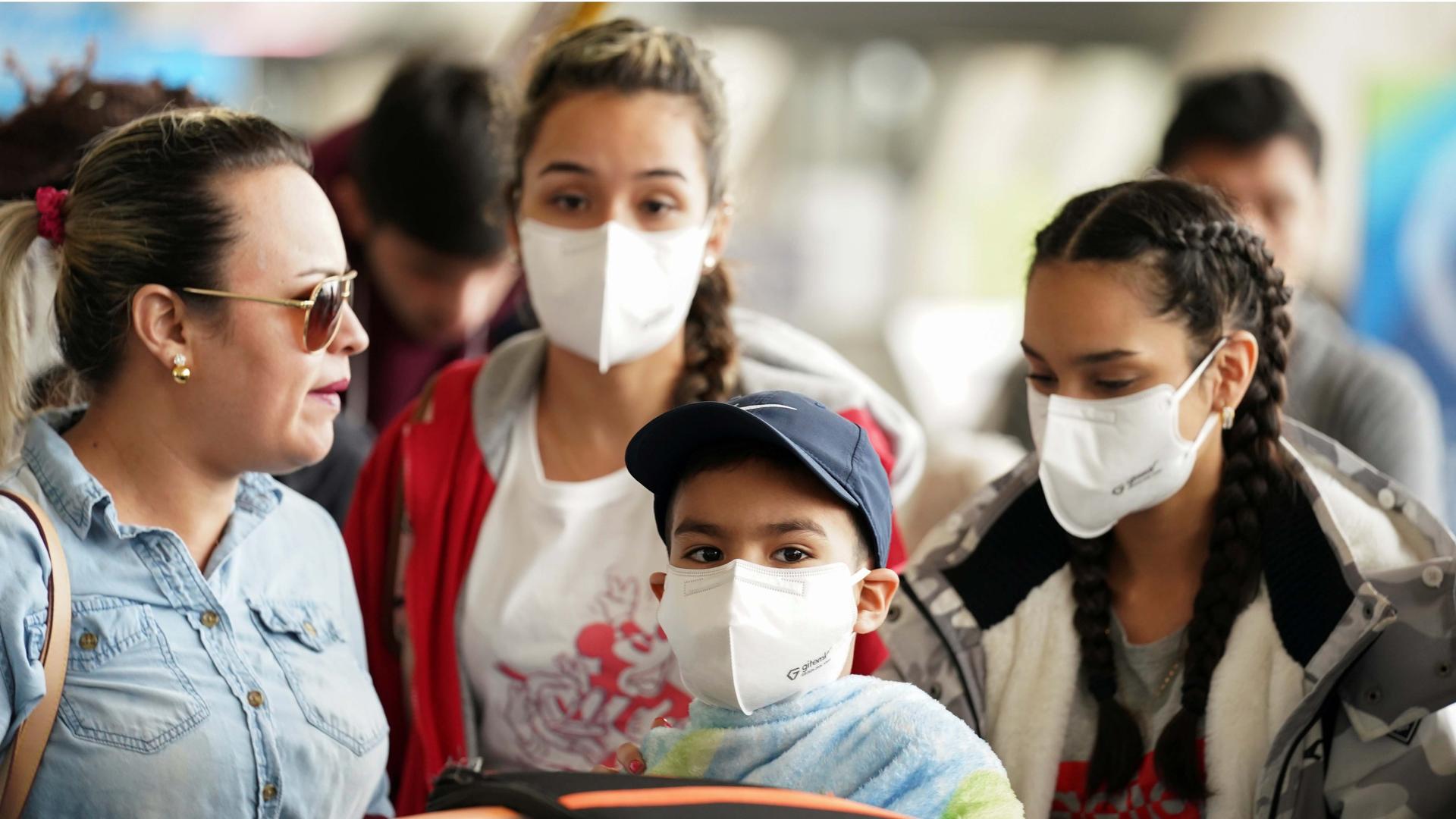 A family wearing face masks queues in a check-in line at Dulles International Airport a day after US President Donald Trump announced travel restrictions on flights from Europe to the United States for 30 days to try to contain the coronavirus, in Dulles.