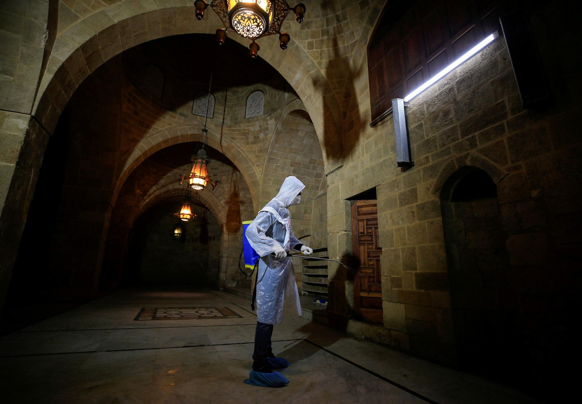 A volunteer in protective gear sanitizes a mosque