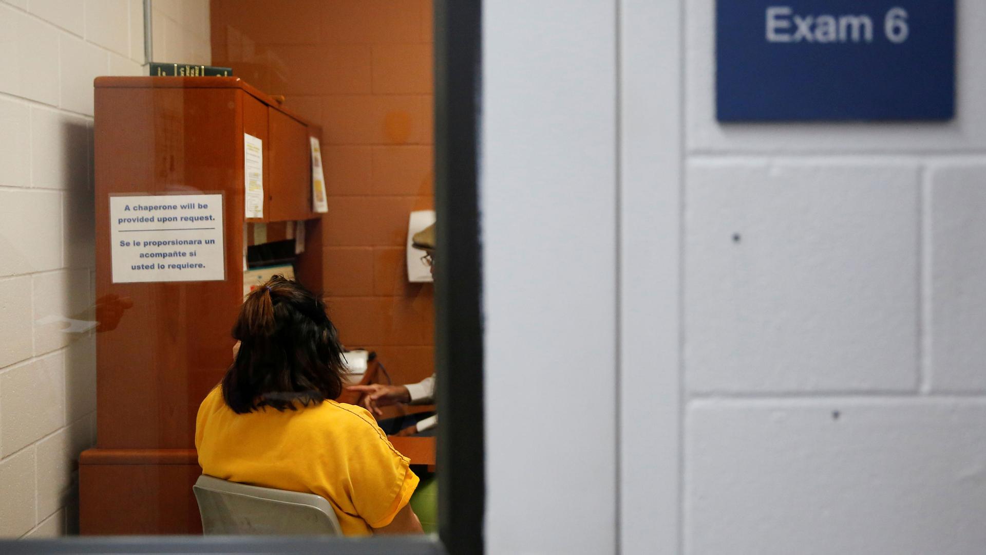 A detainee talks with an employee in an exam room in the medial unit during a media tour at Northwest ICE Processing Center