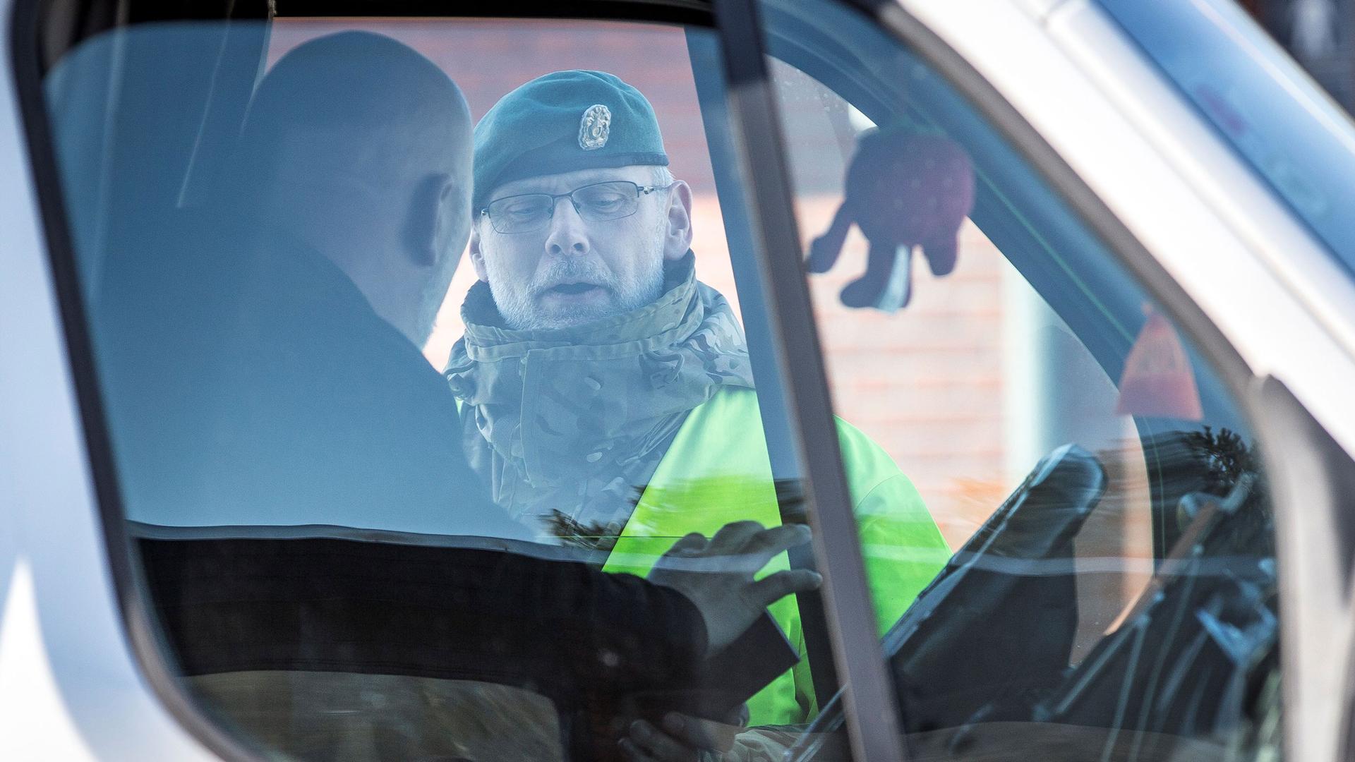 A police officer is shown through the windows of a truck with the driver looking at the officer.