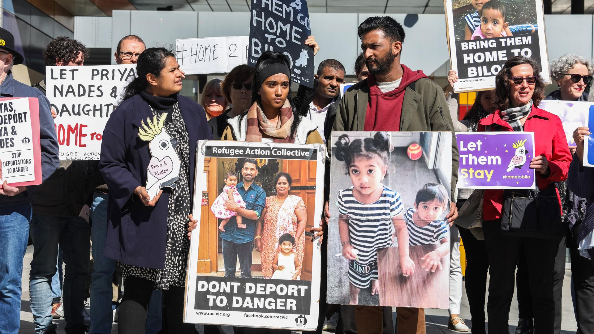 A group of protesters are shown holding placards with pictures of a Tamil family that includes the father, mother and their two small children.