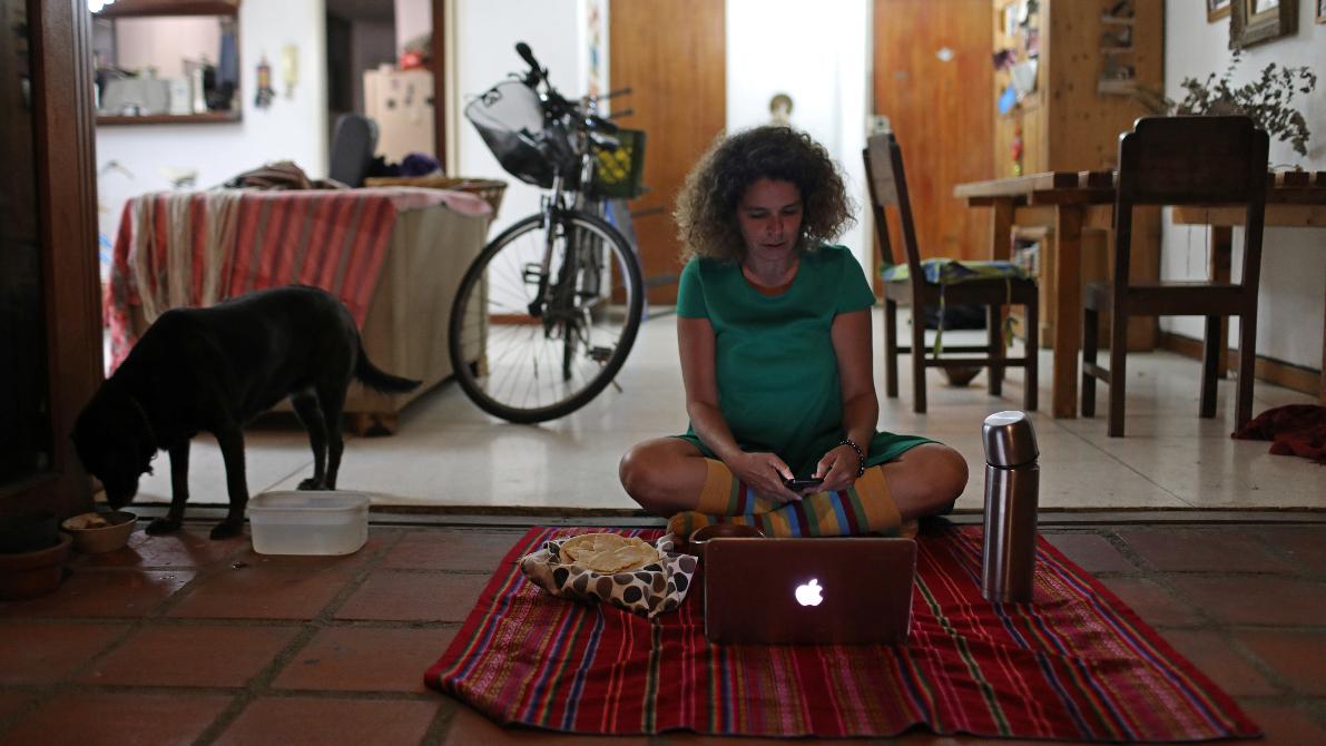 A woman sits on the floor in front of her computer.