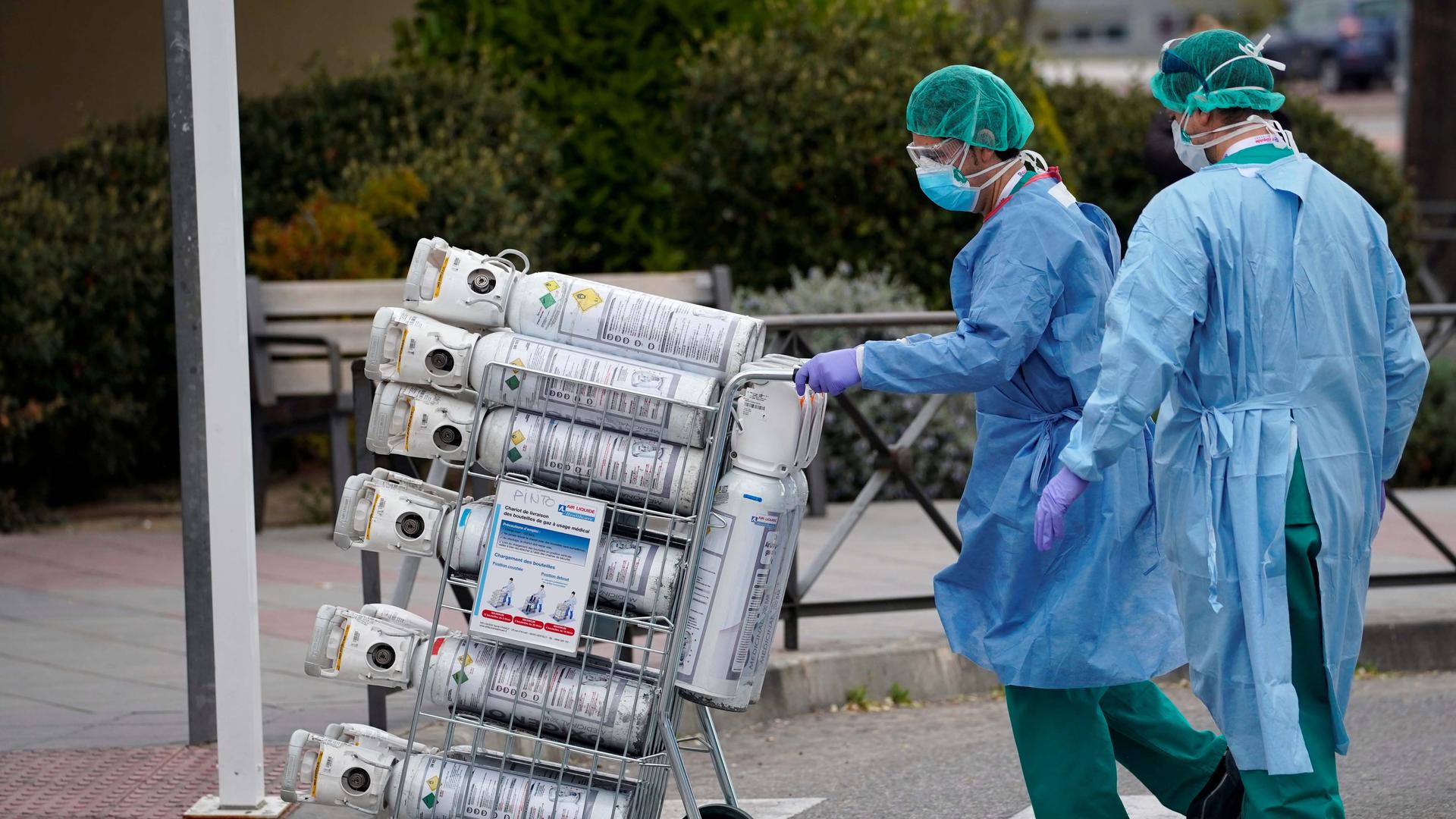Healthcare workers wearing protective face masks bring oxygen bottles to the emergency unit at 12 de Octubre Hospital, amid the coronavirus disease (COVID-19) outbreak in Madrid, Spain March 30, 2020.
