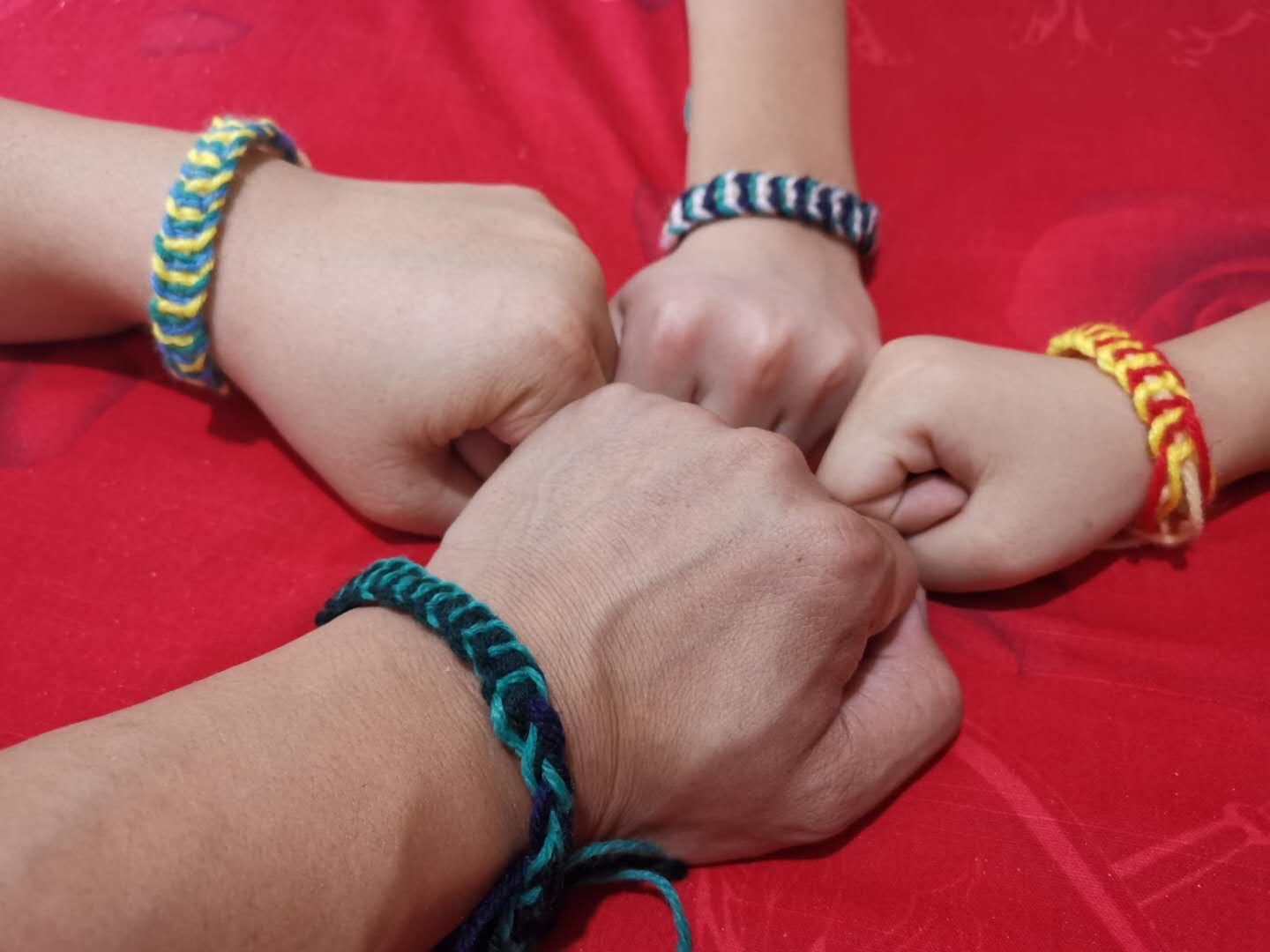 Four arms fist bump to show off their bracelets on their wrists.