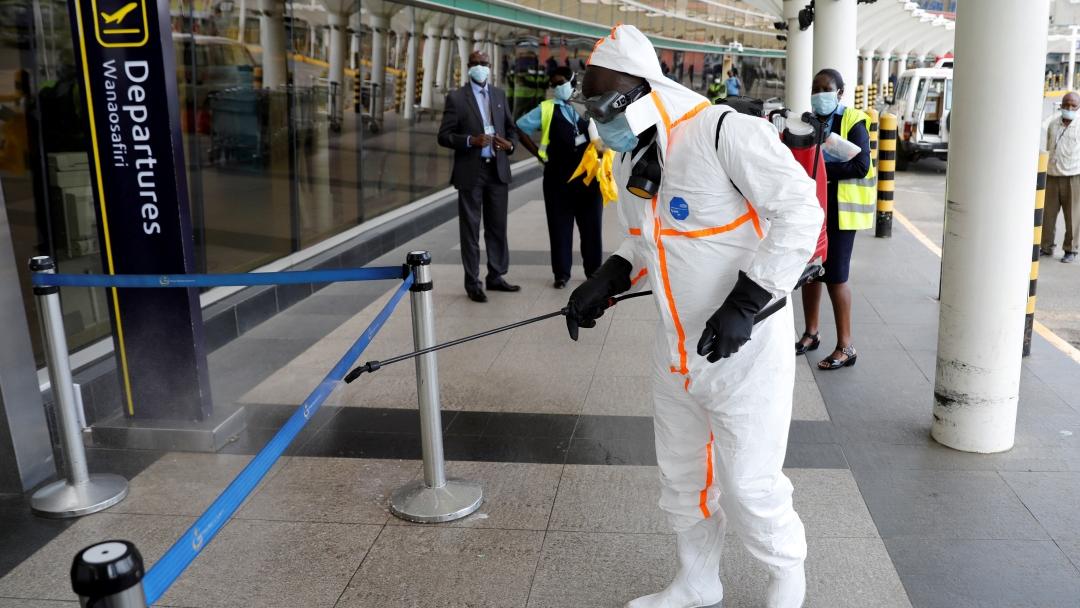 A health worker spray disinfectant at an airport wearing protective gear. 