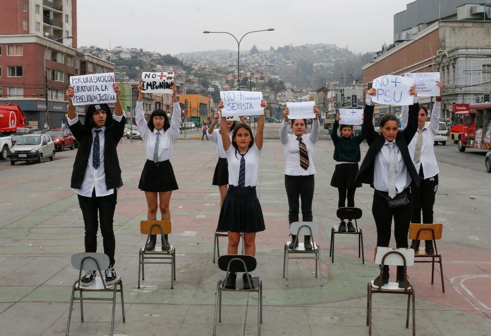 Chilean students standing on classroom holding up protest signs.