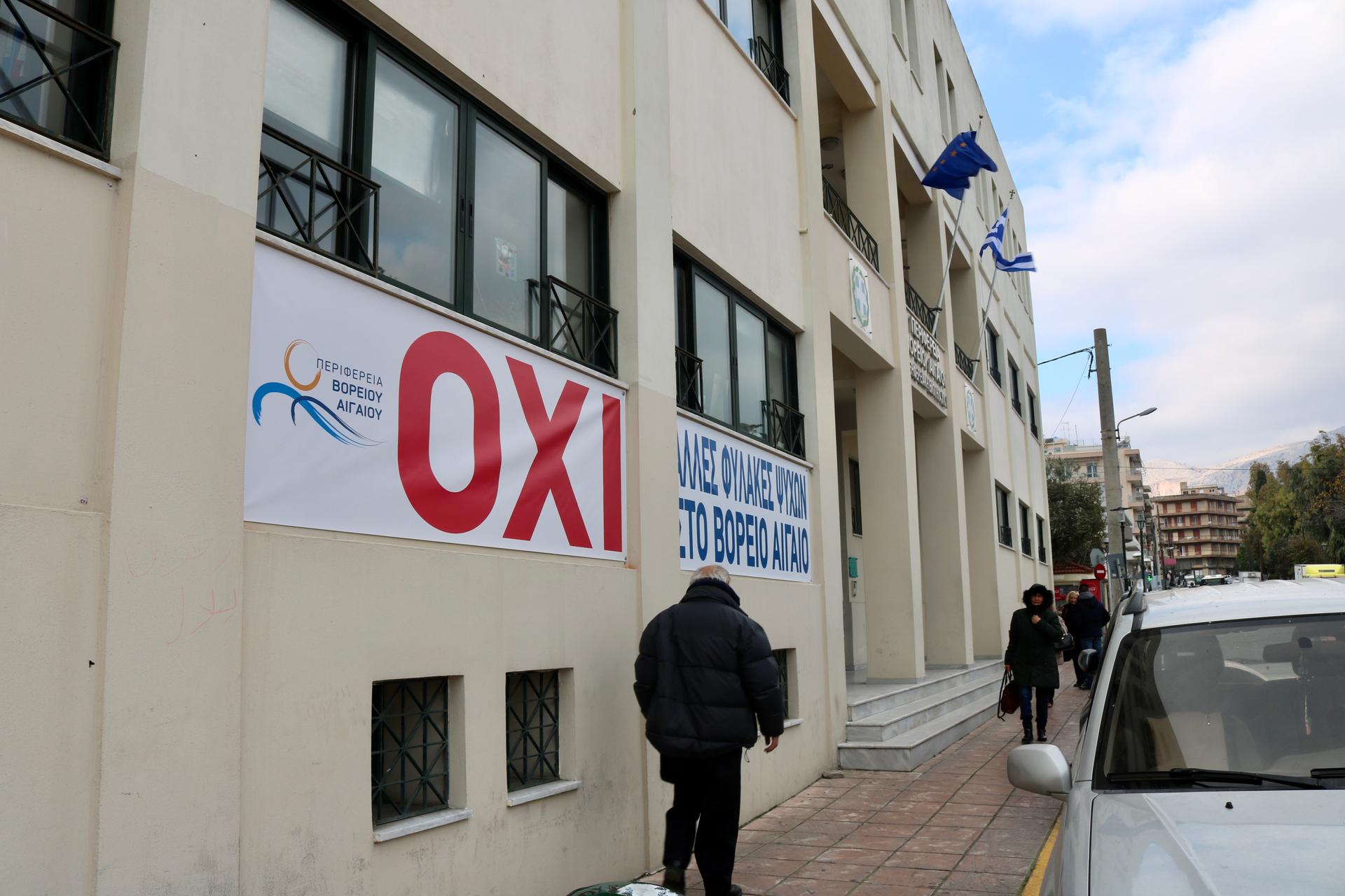 Outside the office of Chios’ regional vice governor, signs in Greek read: “No more prisons in the Northern Aegean.”