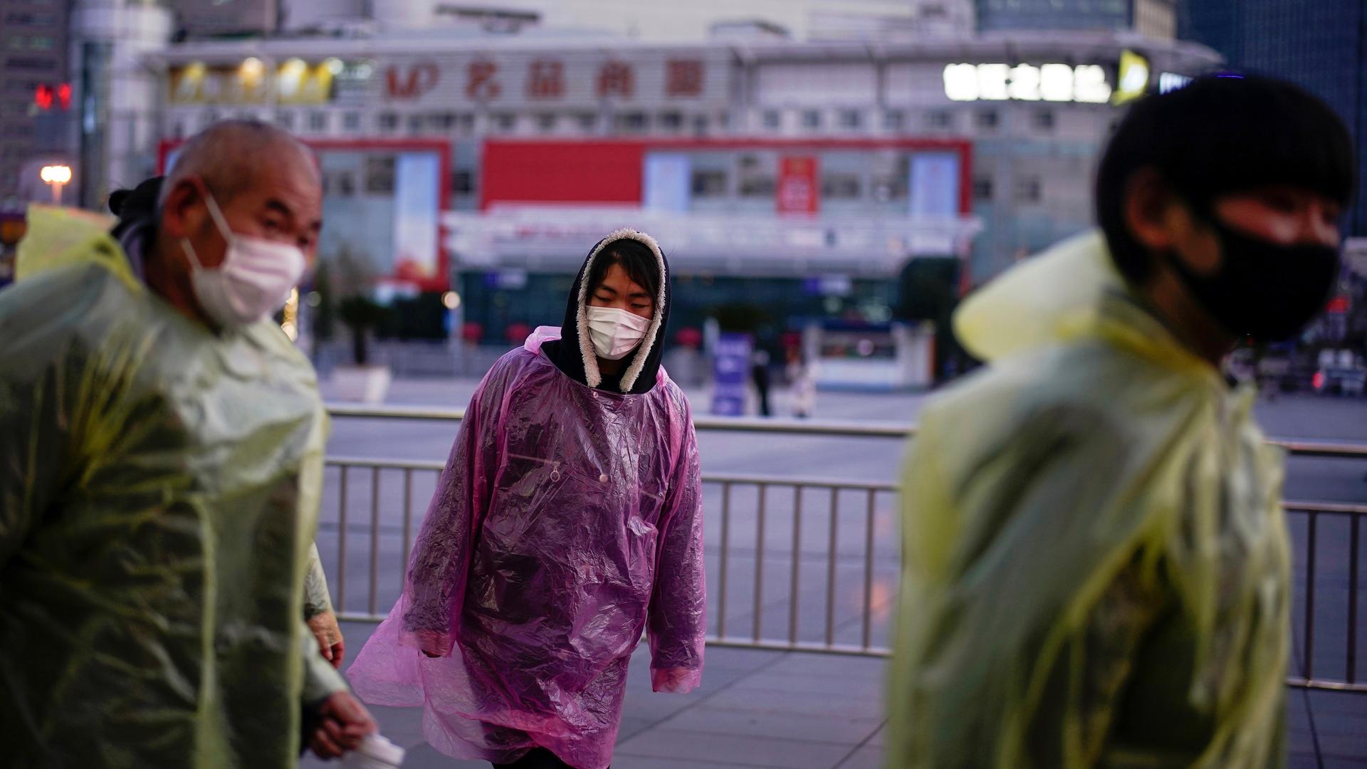 People wear face masks and plastic raincoats as a protection from coronavirus near the Shanghai railway station as the country is hit by an outbreak of the novel coronavirus, in Shanghai, March 5, 2020. 